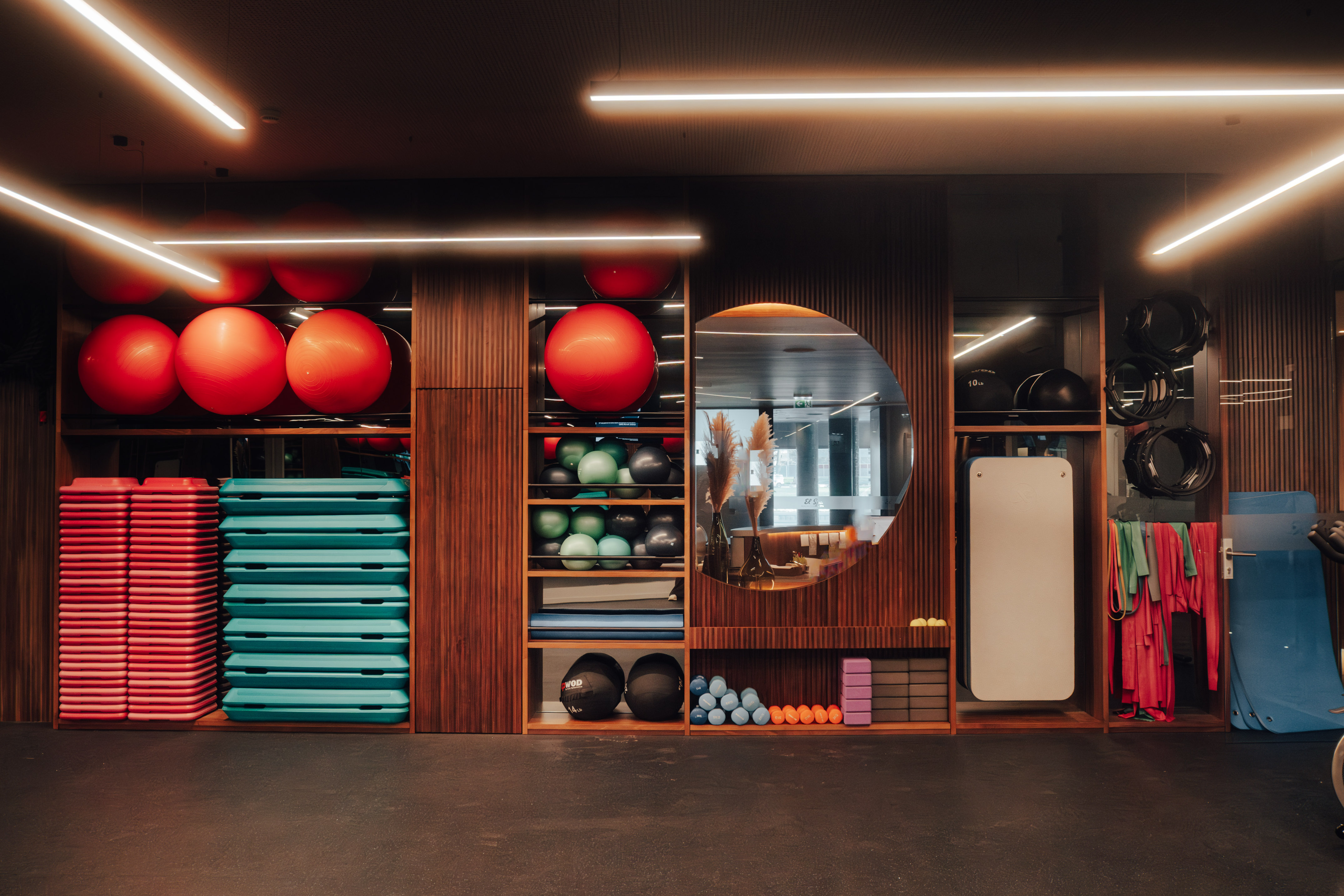 Organized gym with red stability balls, teal steps, and fitness equipment.