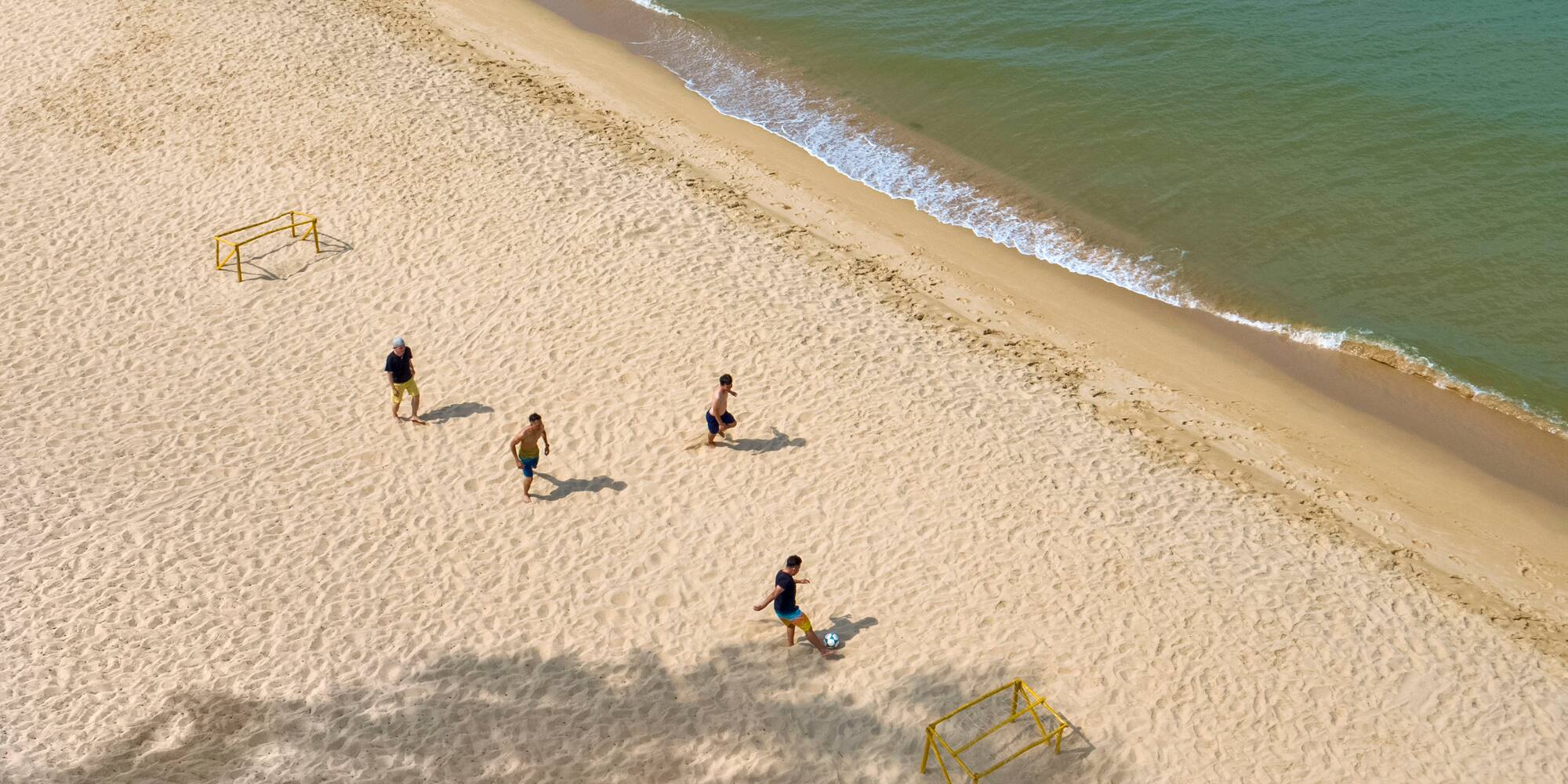 a group of people playing football on a beach