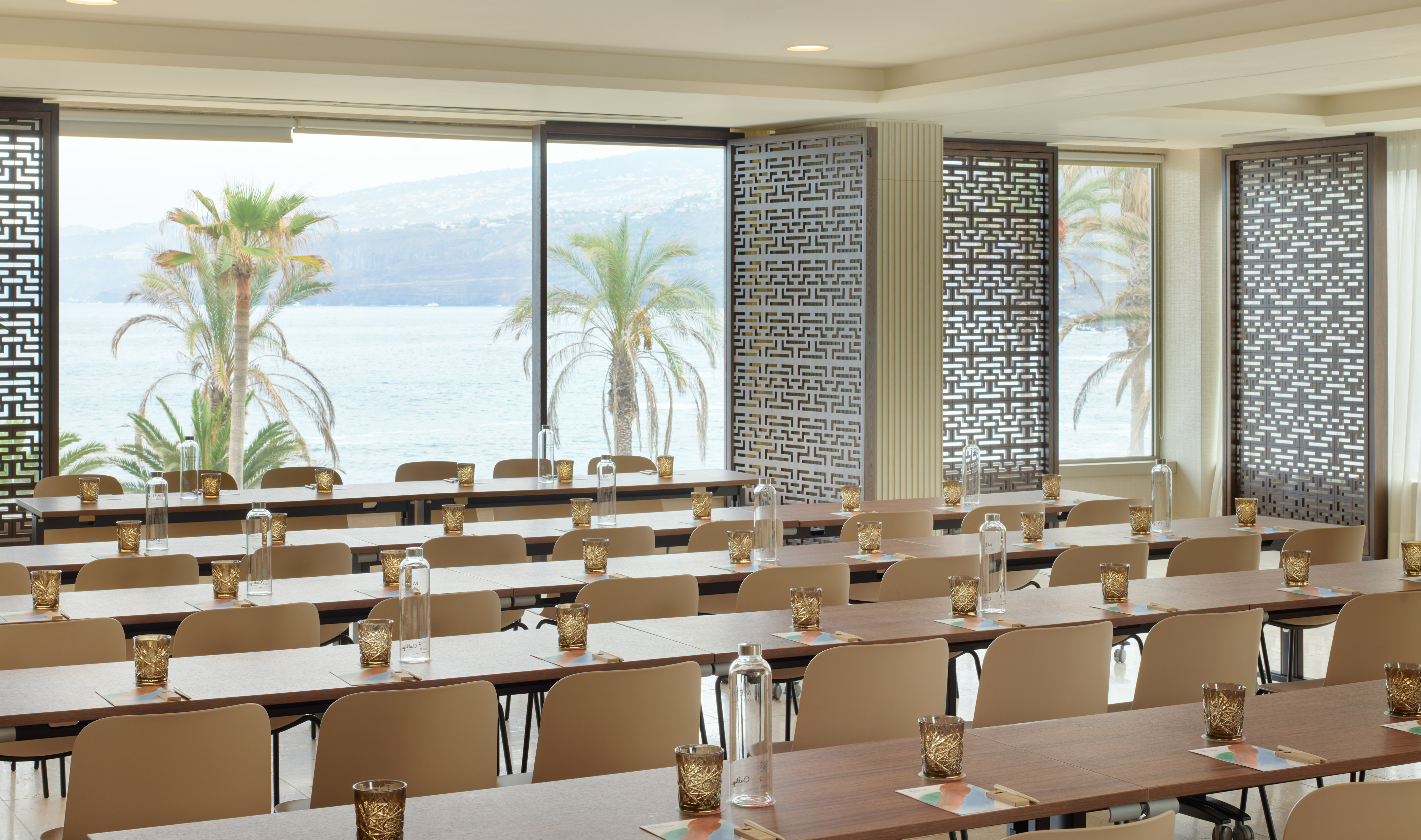 Conference room with ocean view, palm trees, and classroom seating for events.