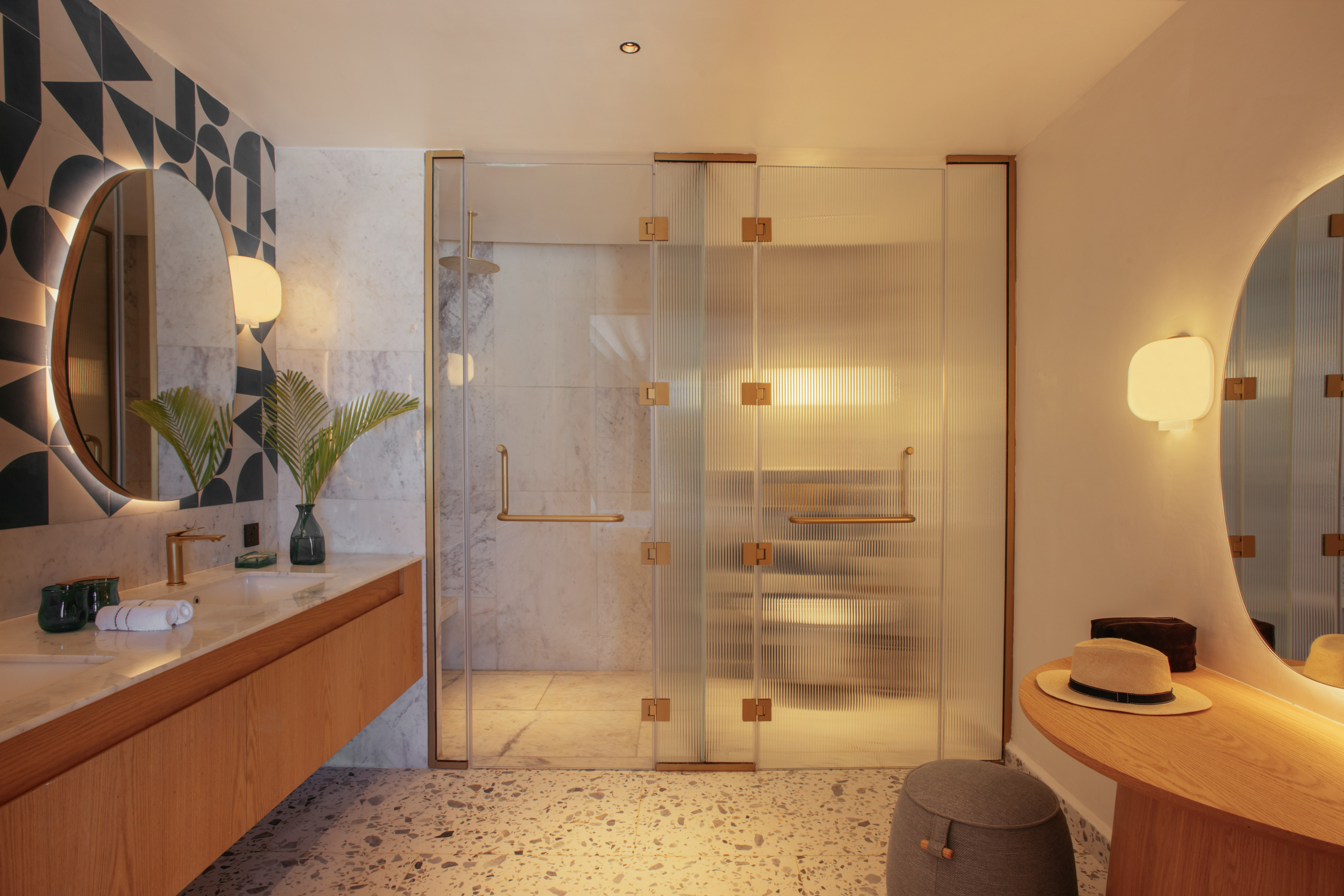 Modern bathroom, wood vanity, backlit mirror, reeded glass shower, terrazzo floor.