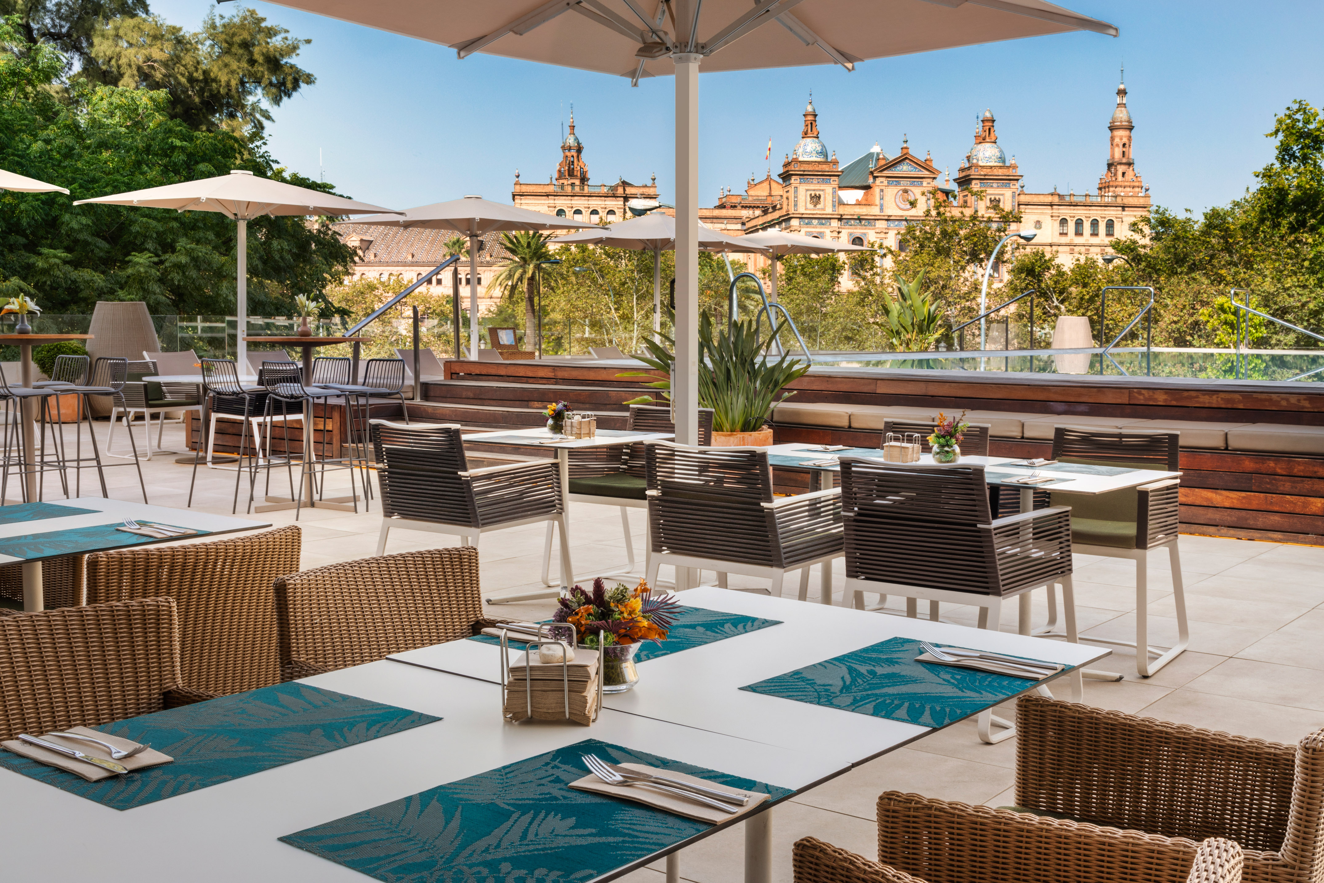 Seville restaurant terrace with dining tables, umbrellas, and historic building.