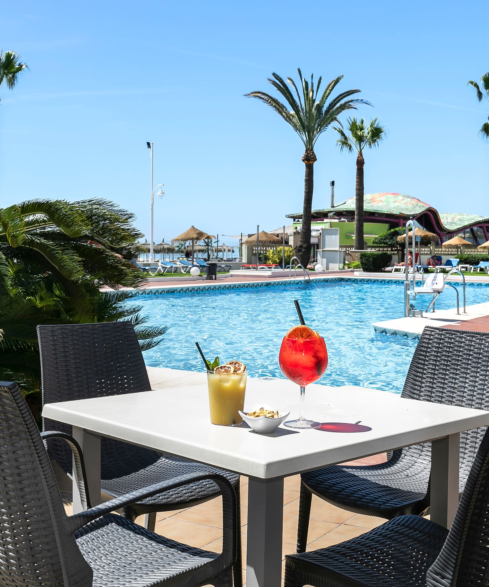 a table with drinks and chairs by a pool