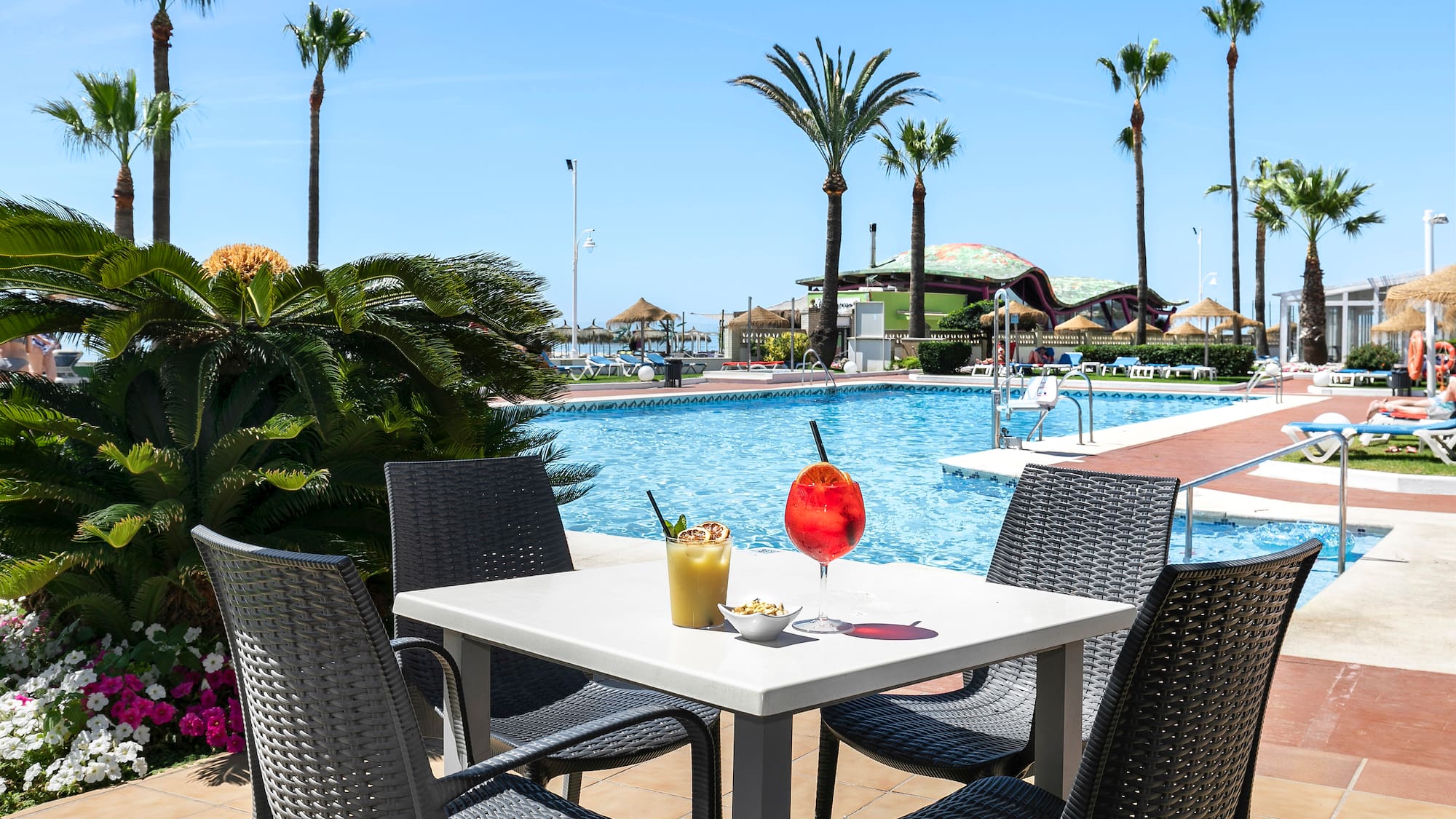 a table with a drink and chairs by a pool