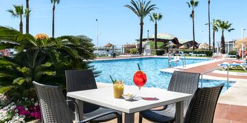 a table with a drink and chairs by a pool