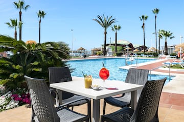 a table with drinks and chairs by a pool