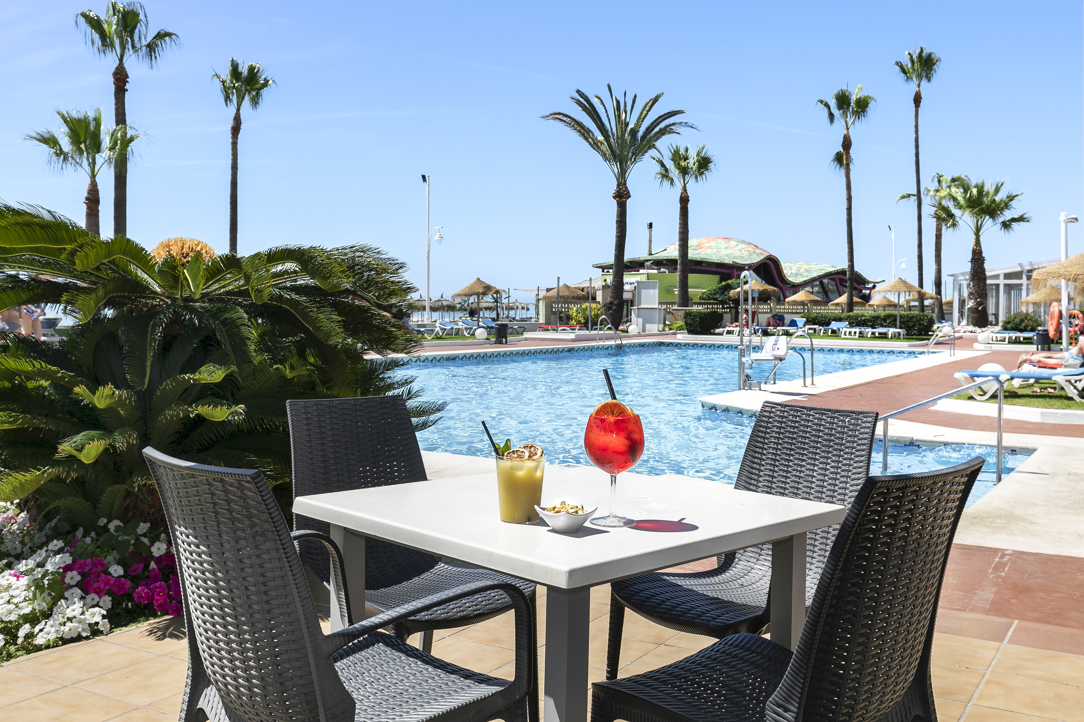 a table with drinks and chairs by a pool
