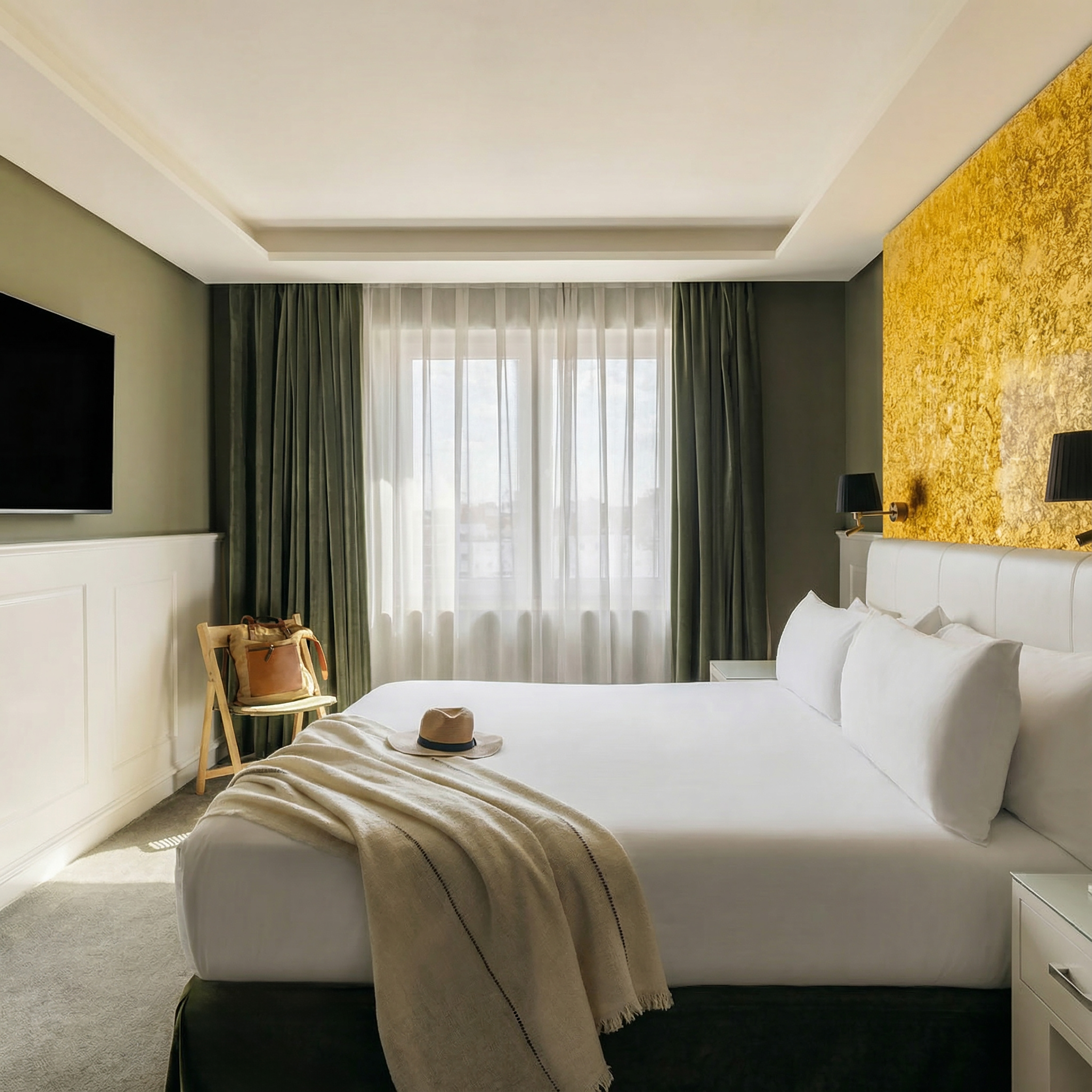Elegant hotel room with king bed, gold accent wall, green curtains.