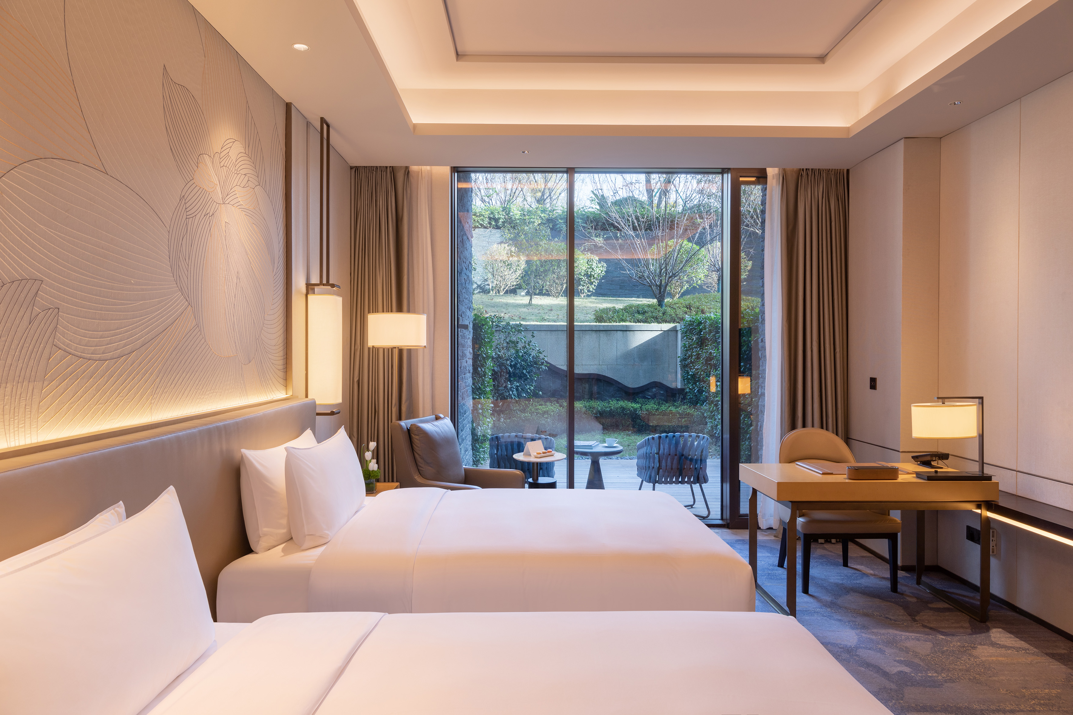 Modern hotel twin bedroom with garden view, desk, and elegant decor.