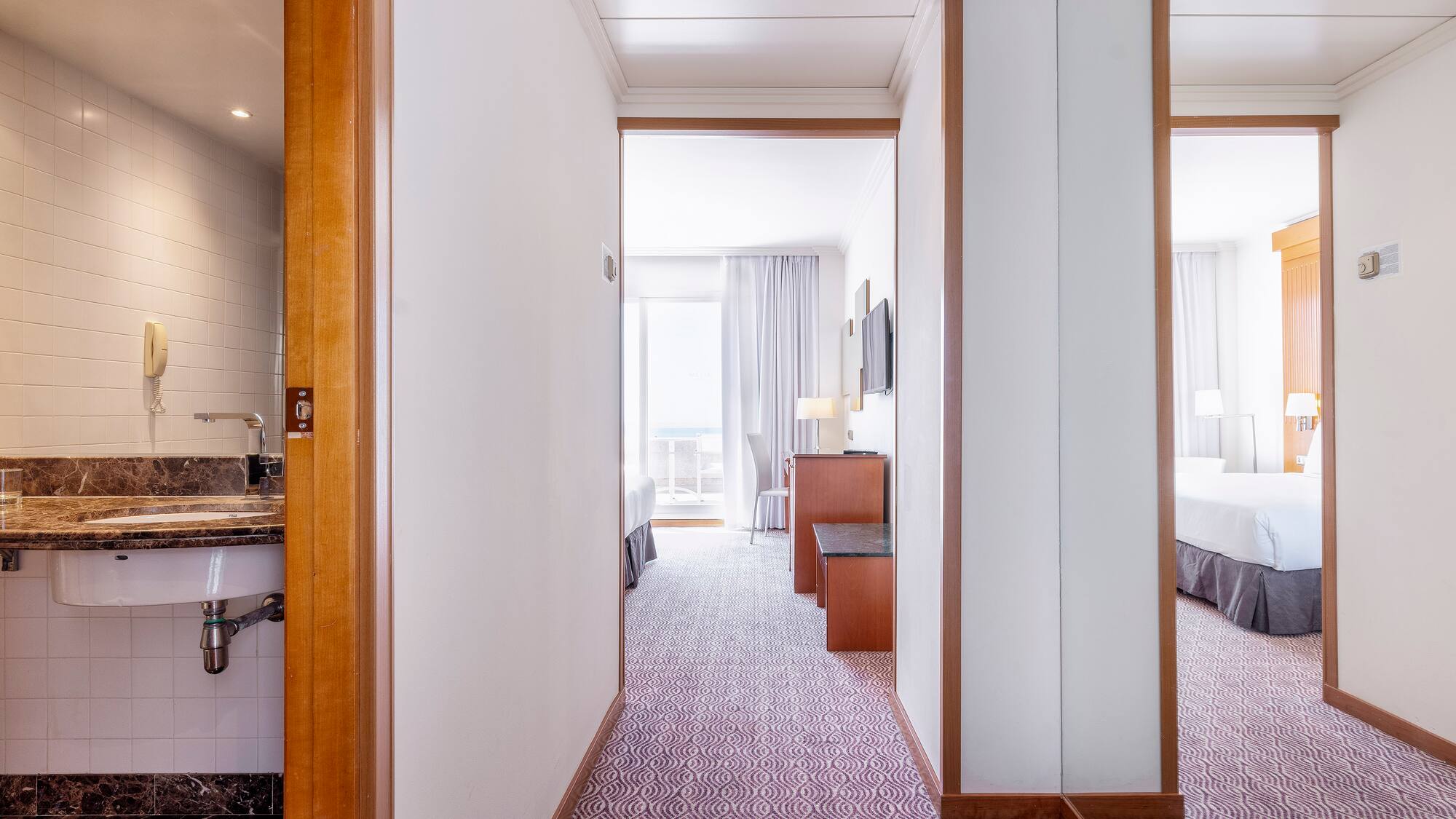 a hallway with a bed and a sink