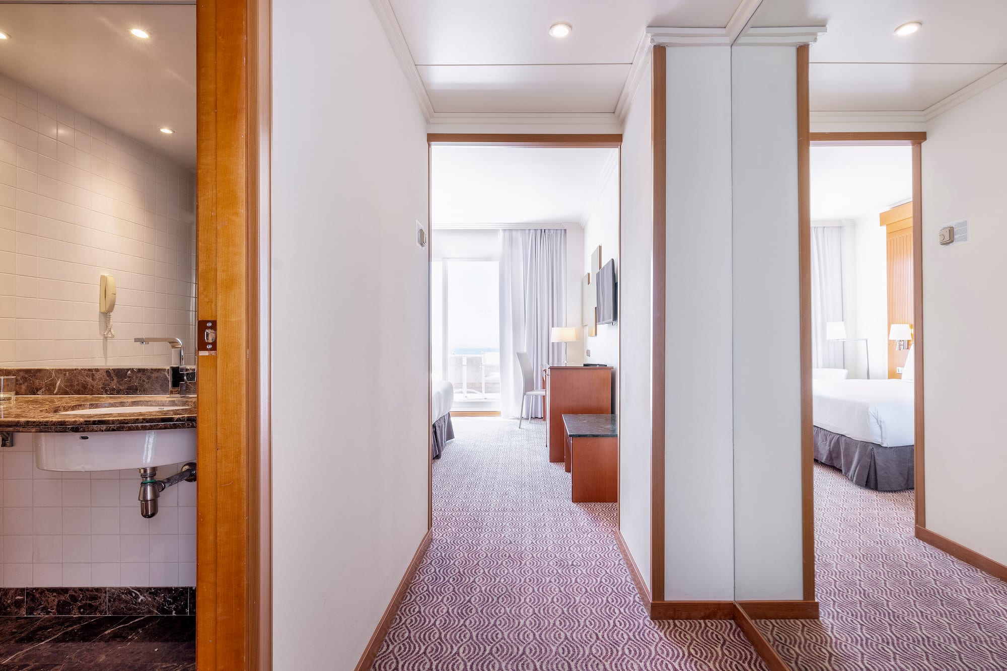 a hallway with a bed and a sink