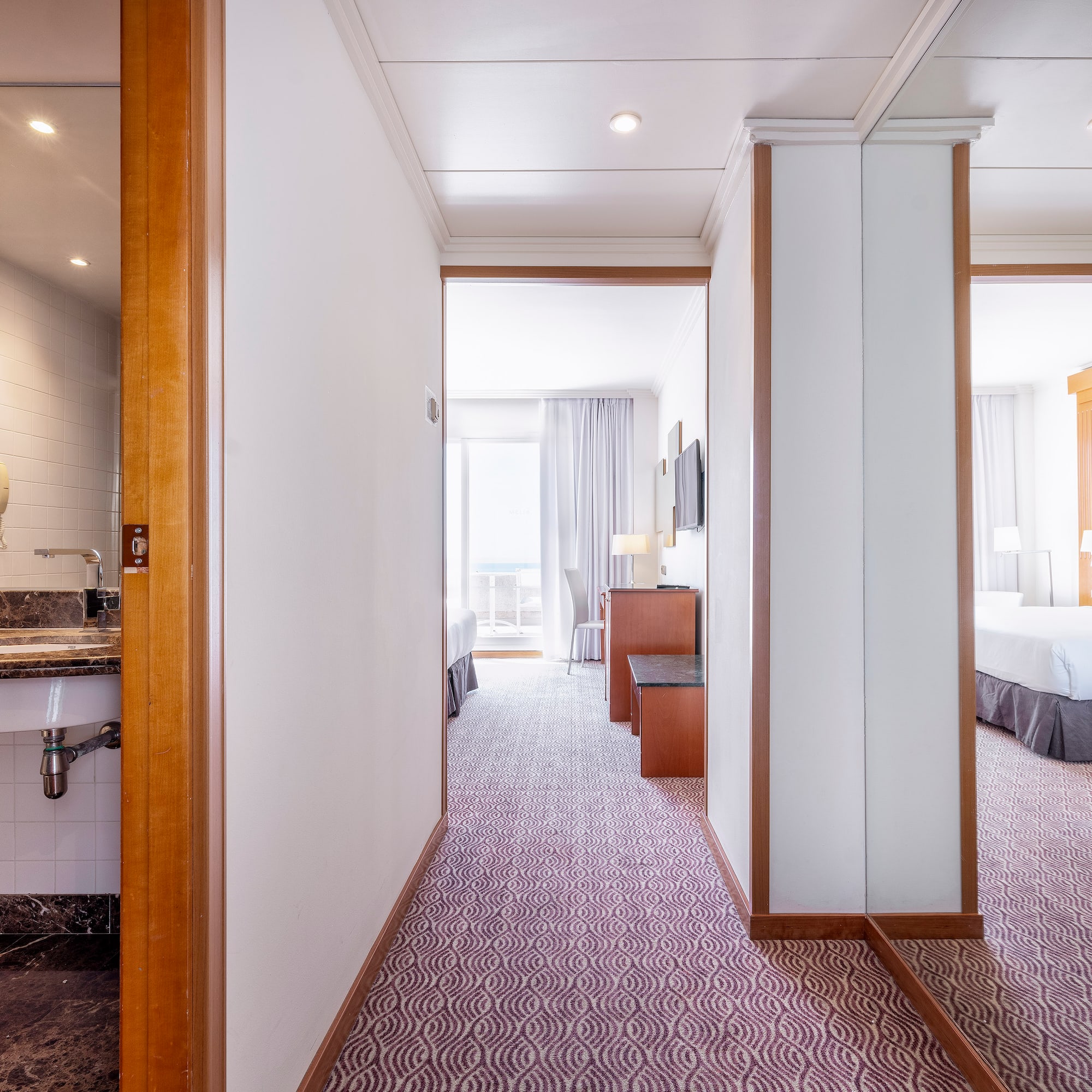 a hallway with a bed and a sink