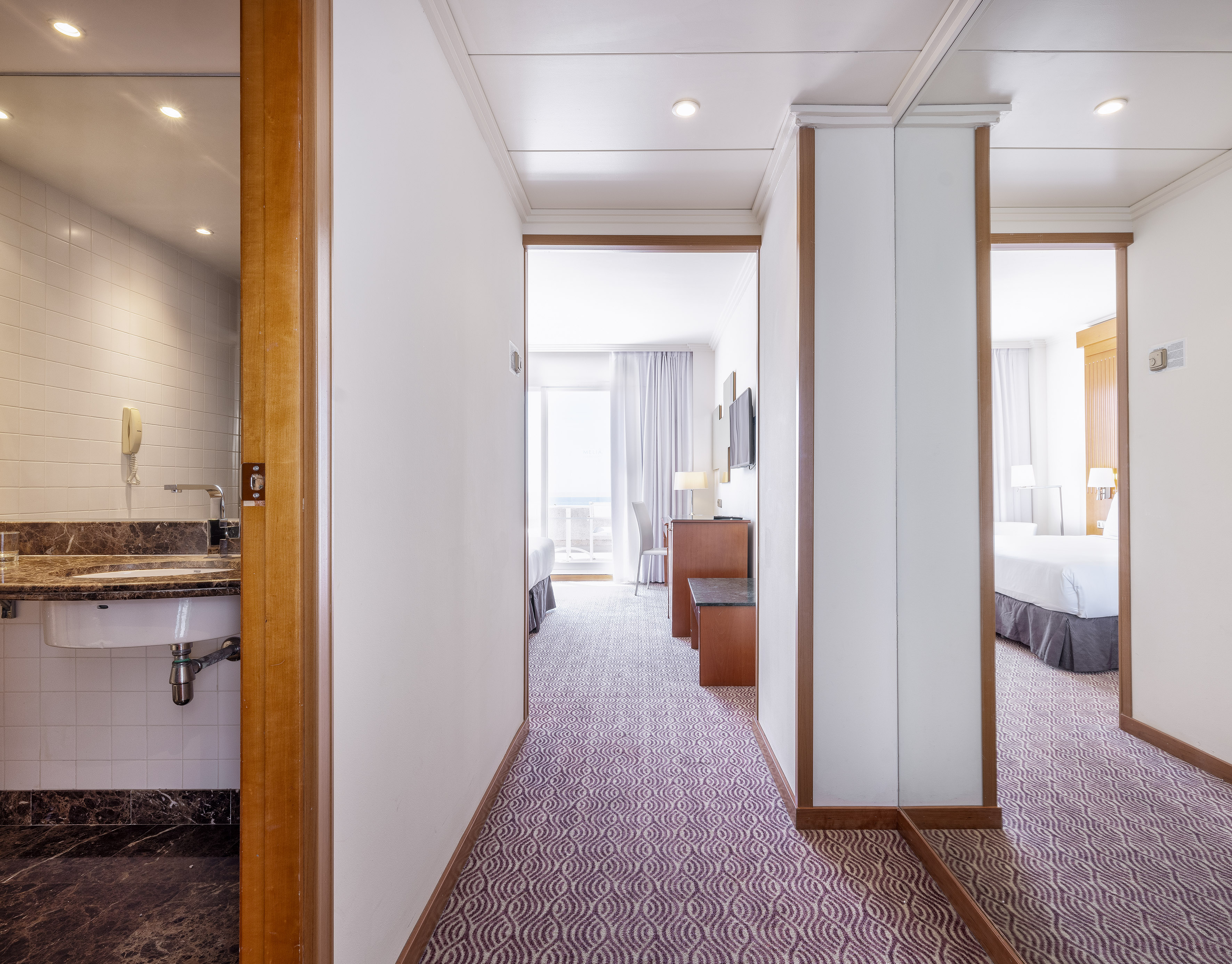 a hallway with a bed and a sink