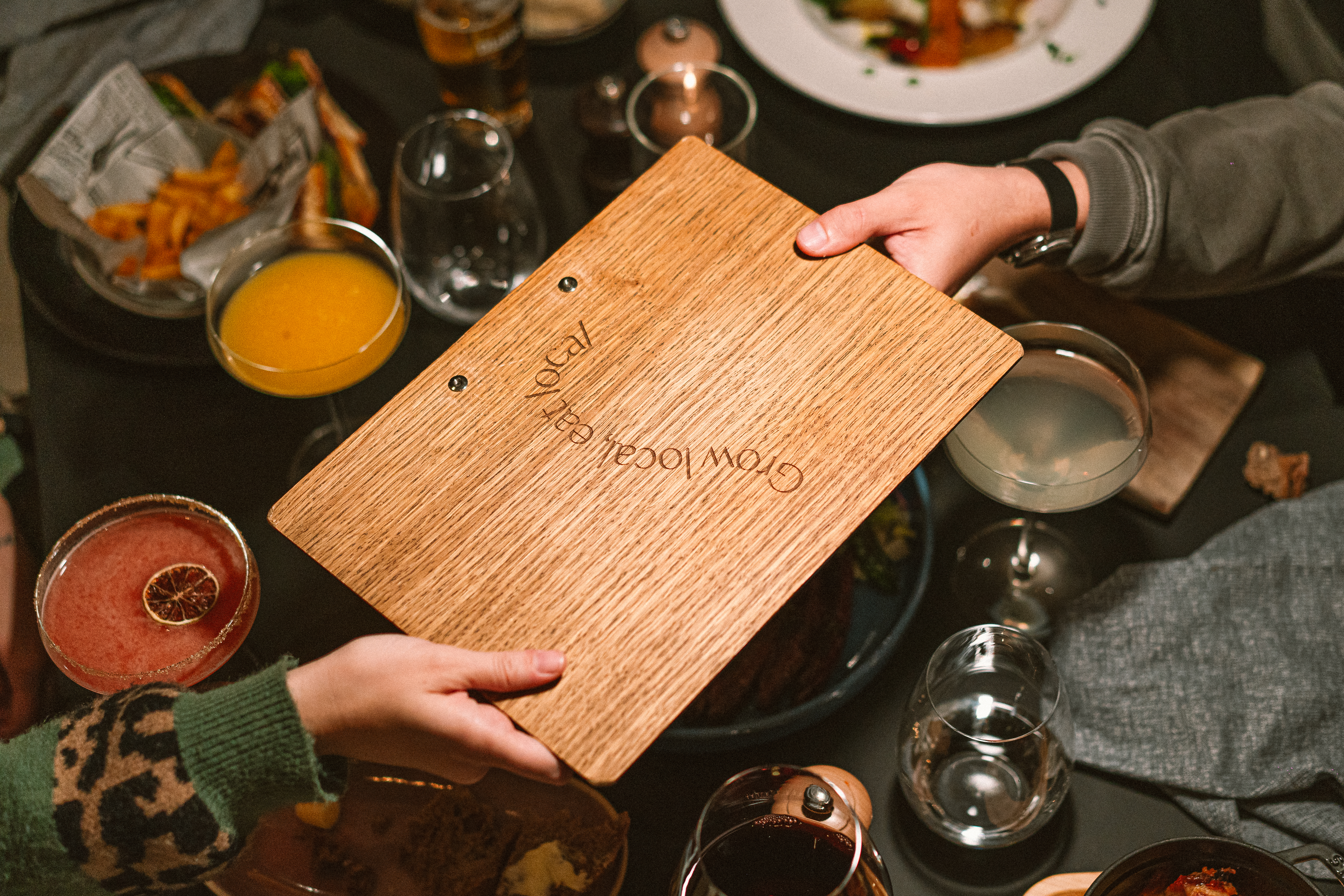 "Grow local, eat local" menu board held, dining table with cocktails and food. - De Gaart, Cuisine locale - INNSiDE Luxembourg, Luxembourg