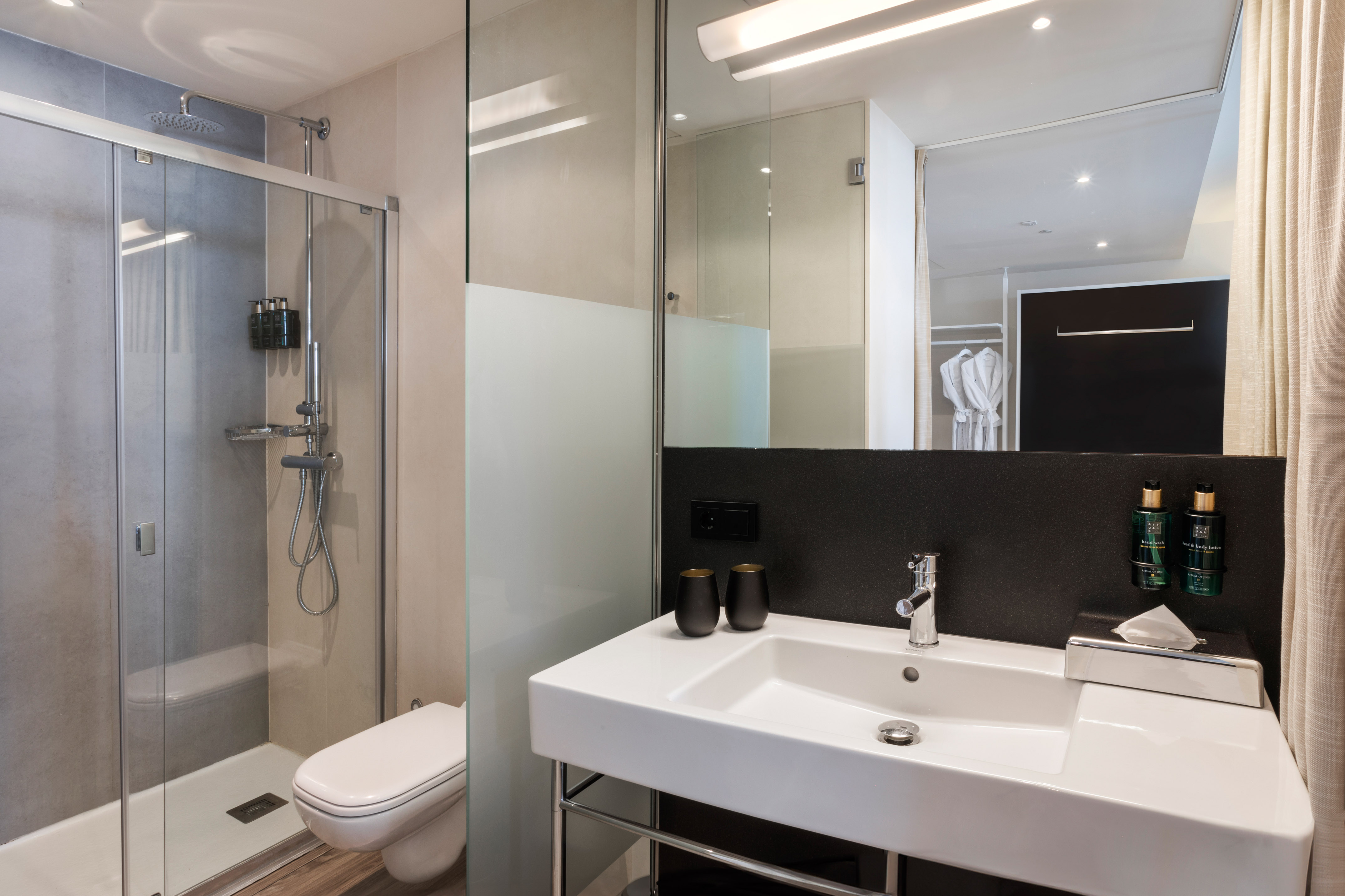 Modern hotel bathroom with glass shower, toilet, and sleek vanity sink.