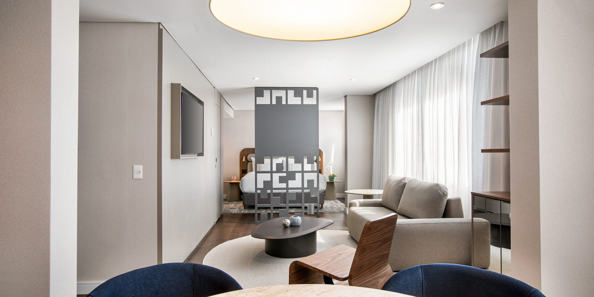 Modern hotel suite with open-plan living room, bedroom, and dining space.