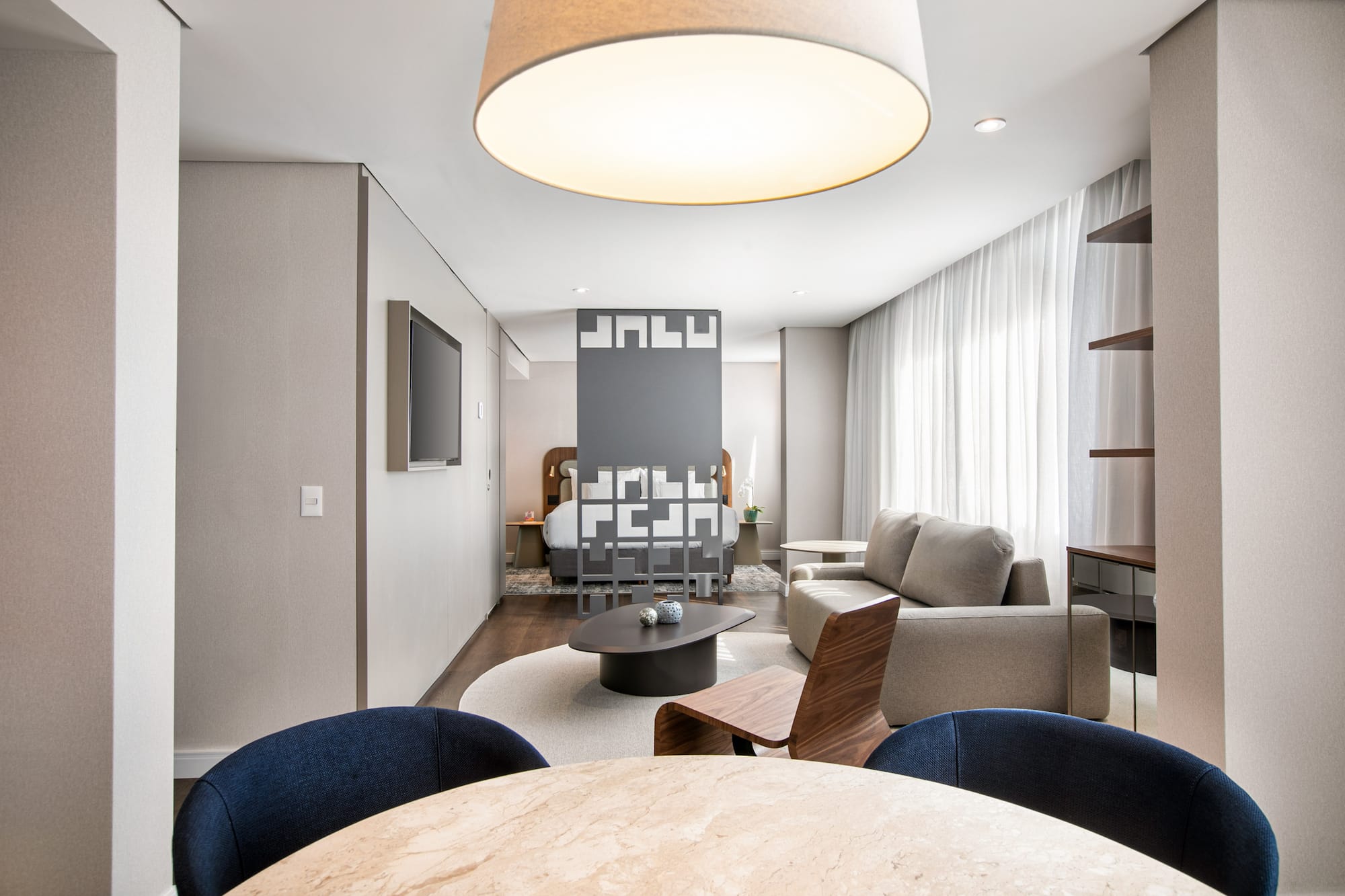 Modern hotel suite with open-plan living room, bedroom, and dining space.