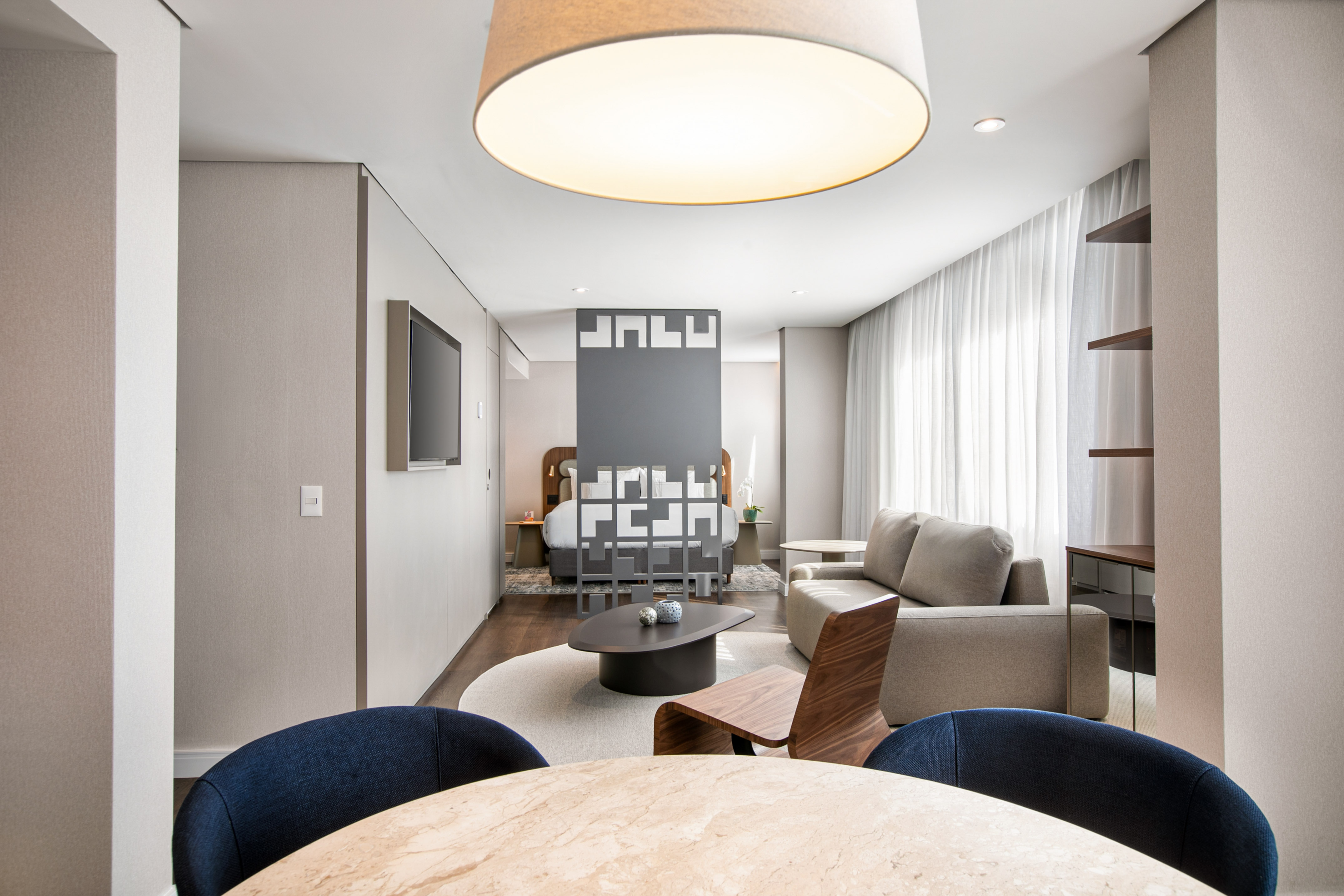 Modern hotel suite with open-plan living room, bedroom, and dining space.