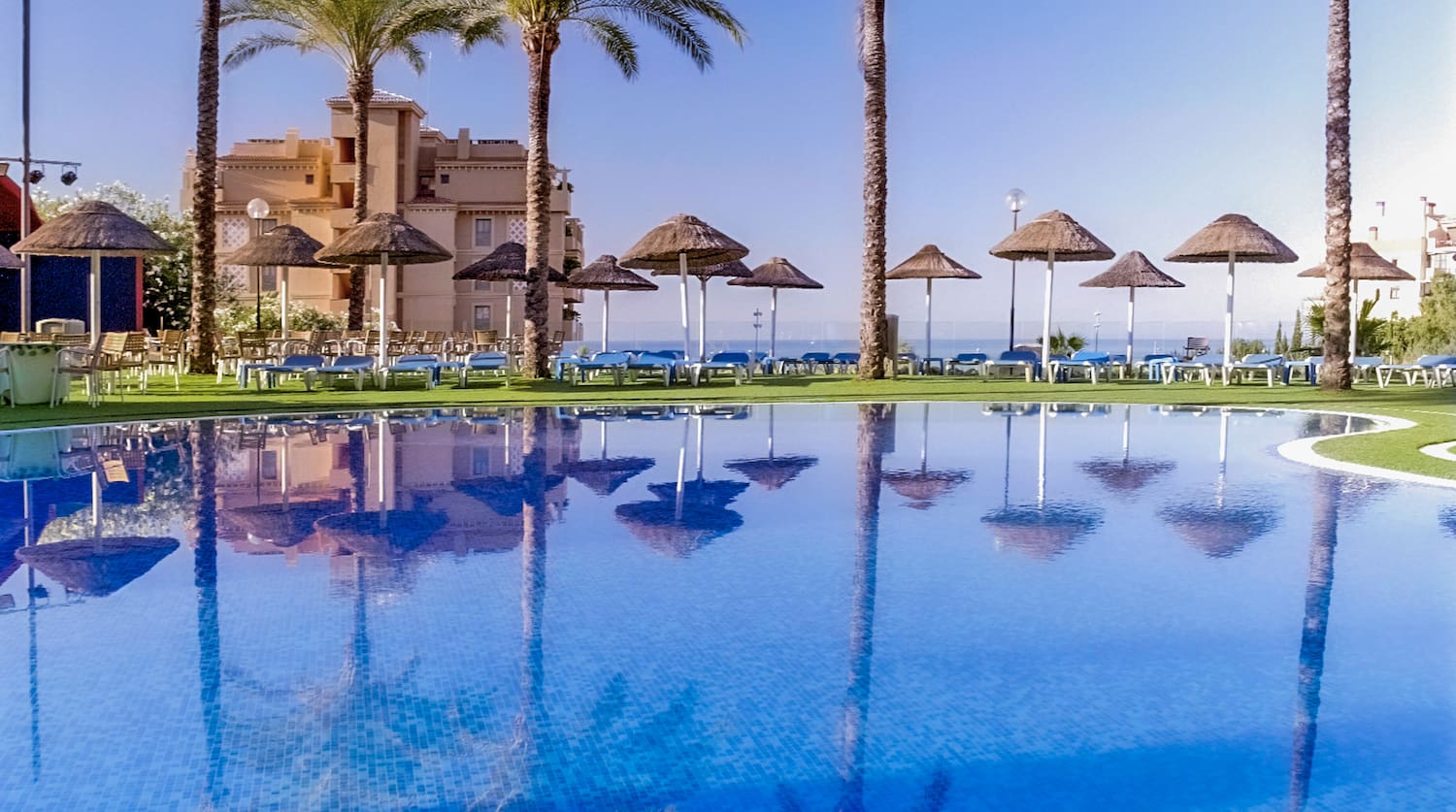 a pool with palm trees and umbrellas