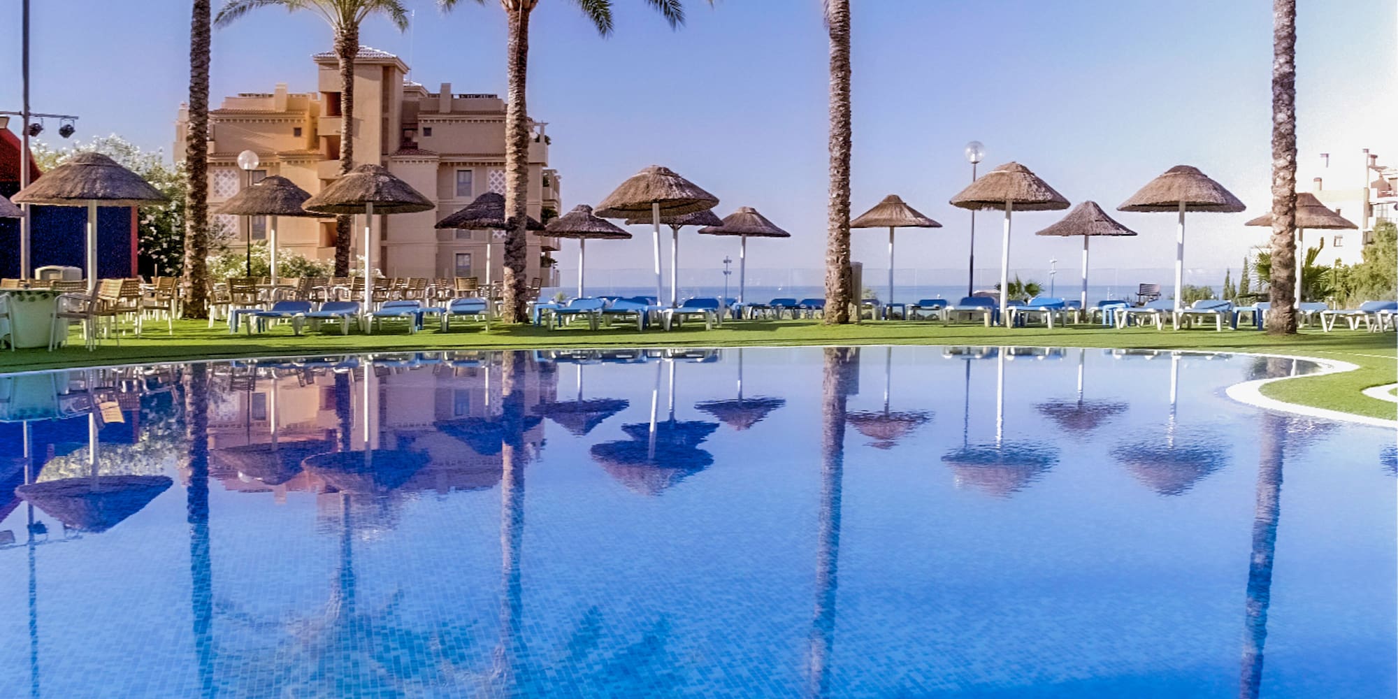 a pool with palm trees and umbrellas