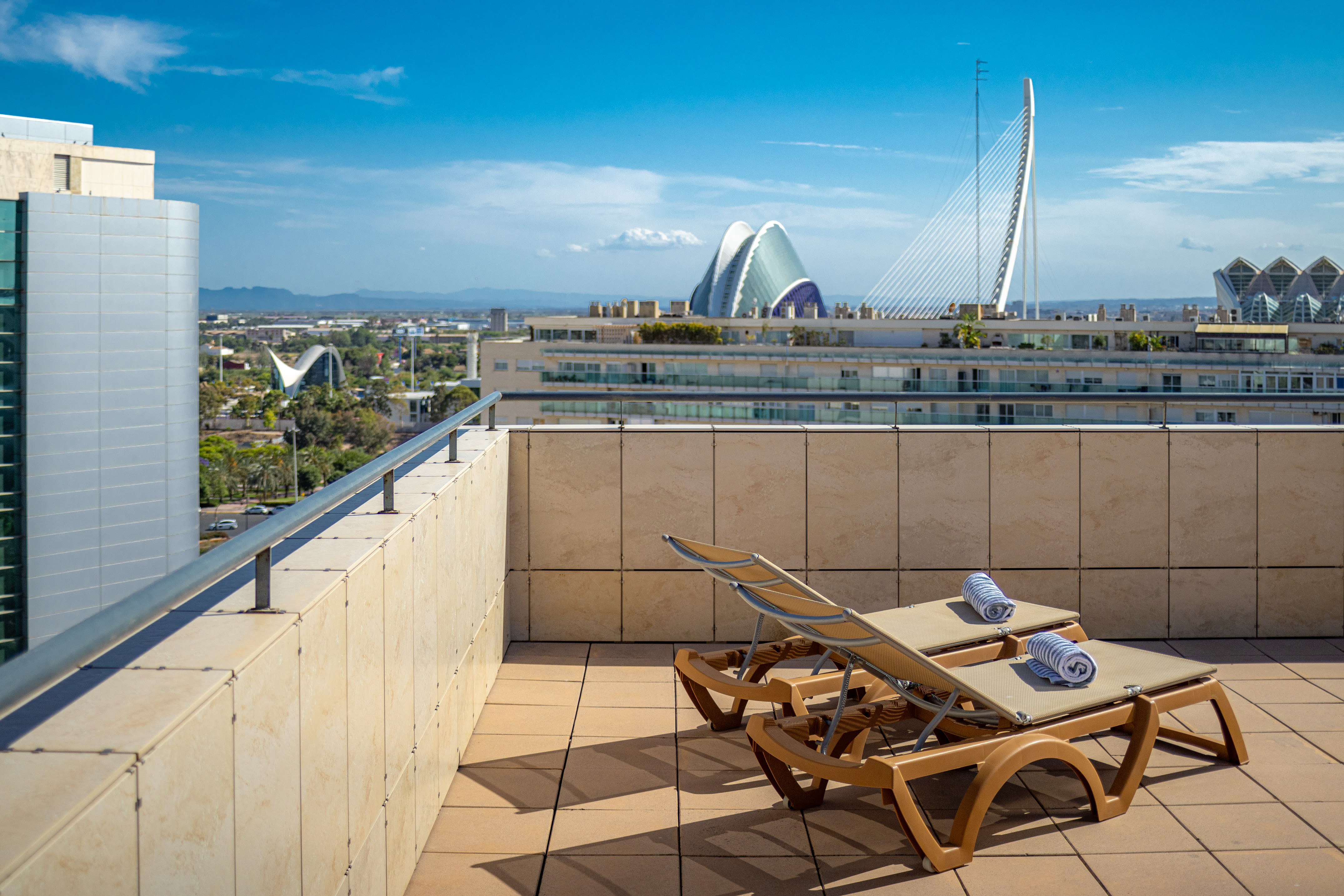 Rooftop terrace with sun loungers overlooking Valencia's City of Arts and Sciences.