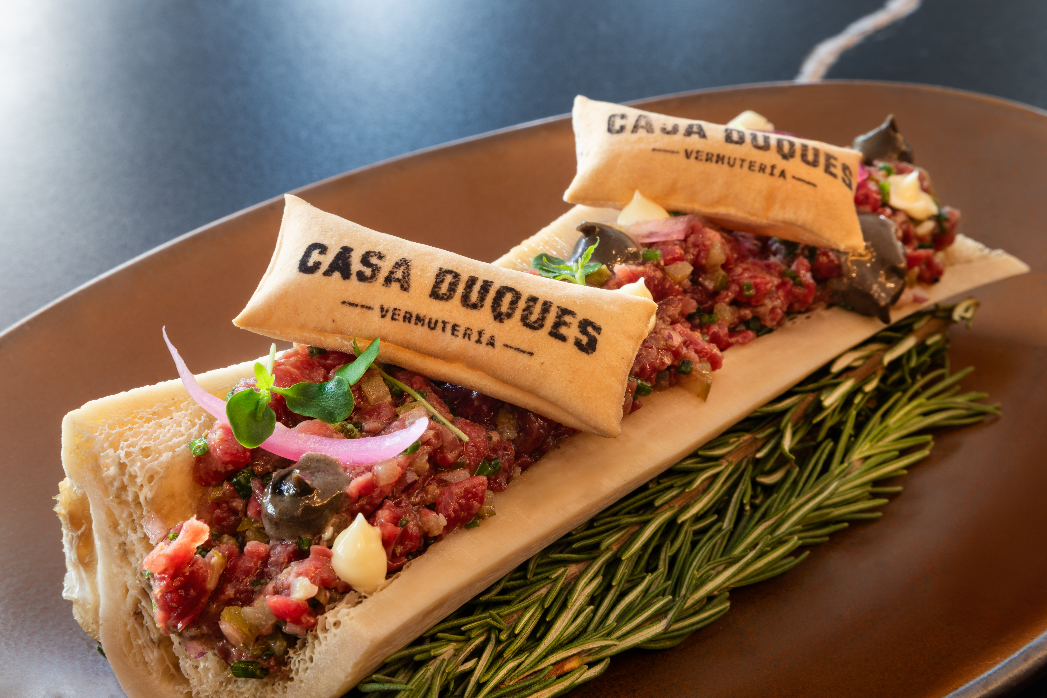 Beef tartare in bone marrow with Casa Duques crackers, microgreens, and rosemary.