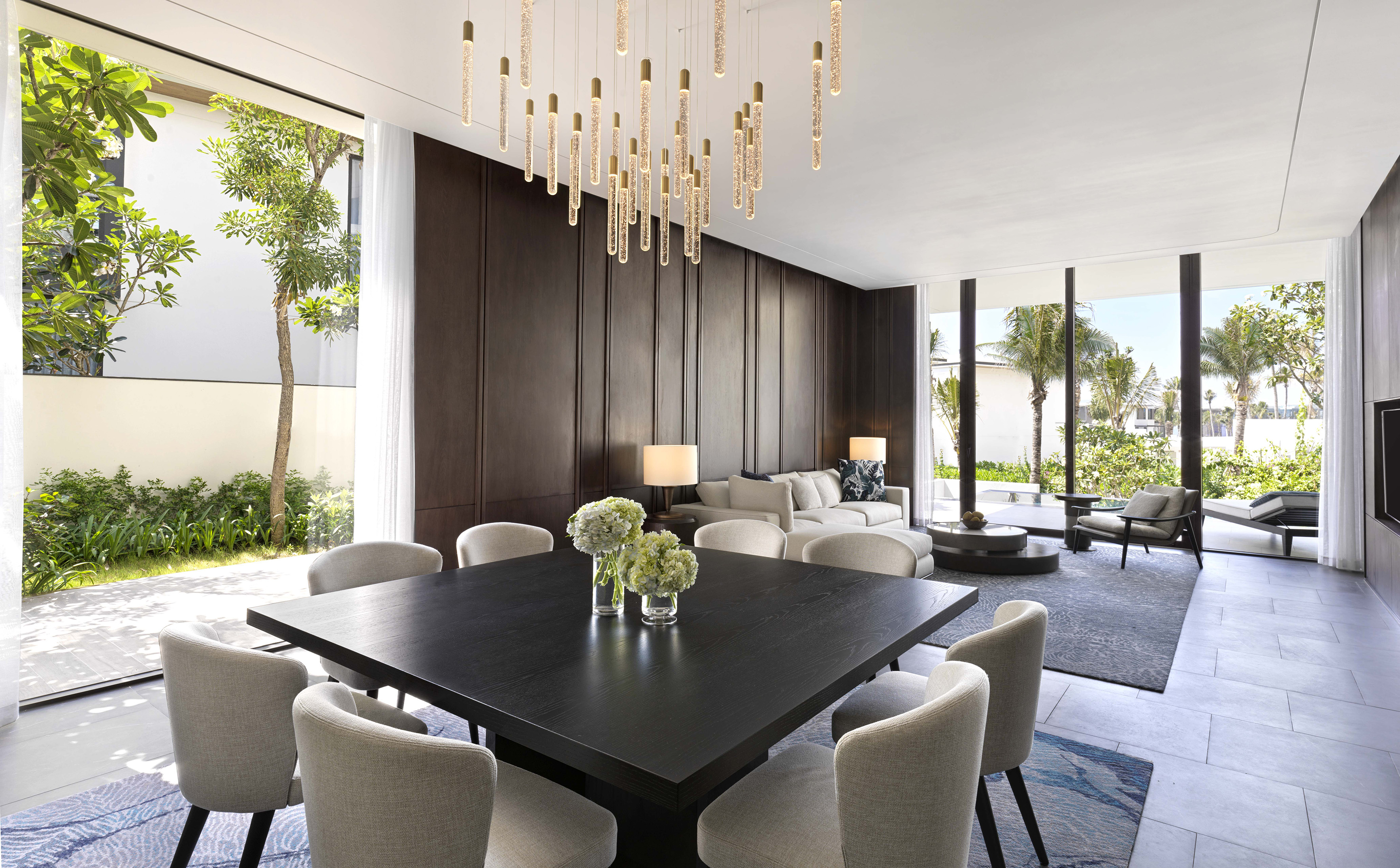 Modern dining room with contemporary chandelier, square table, and garden view.