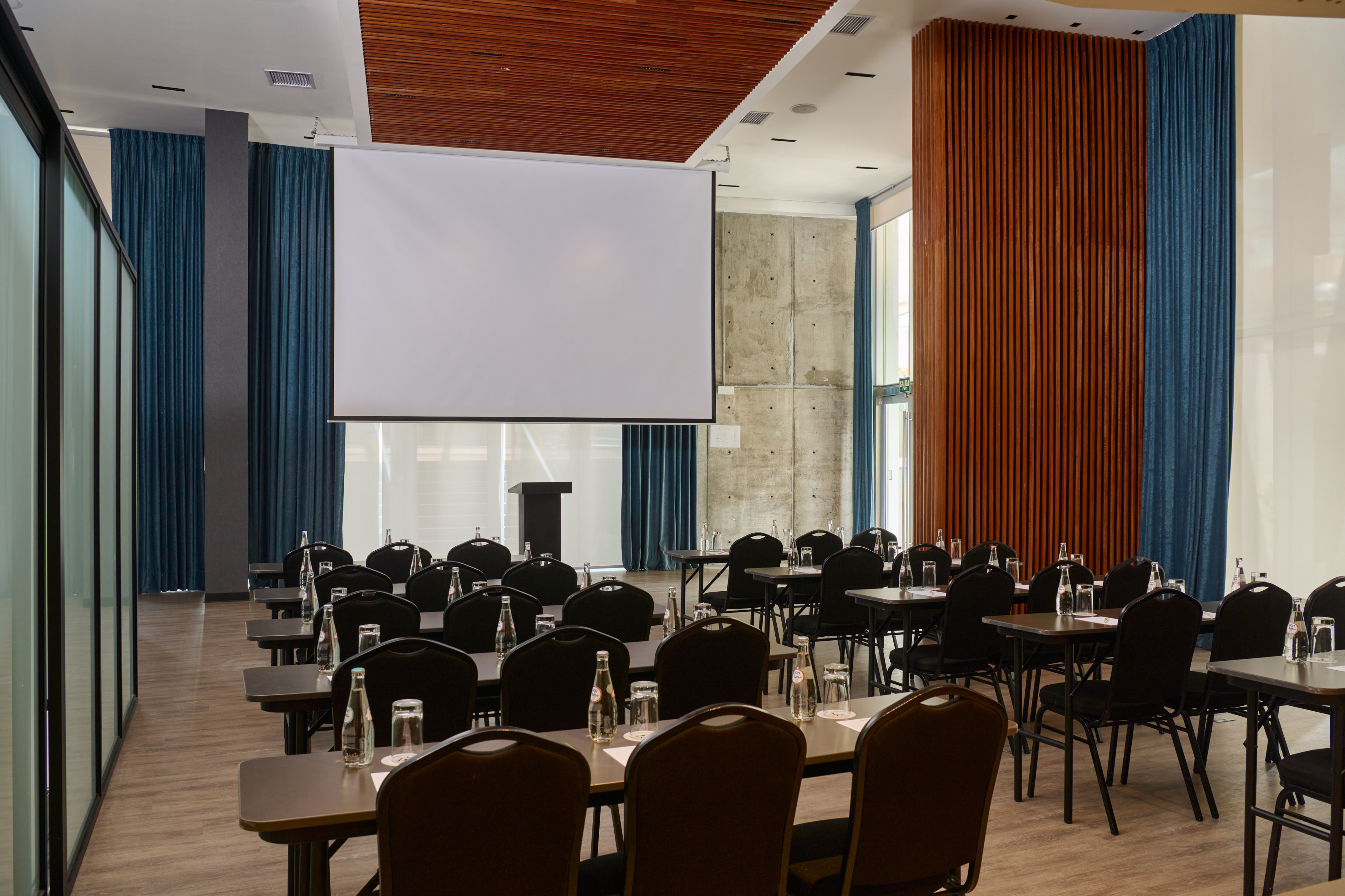 Empty modern meeting room with projector screen, podium, and arranged seating.