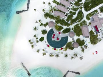 an aerial view of a beach with a pool and houses