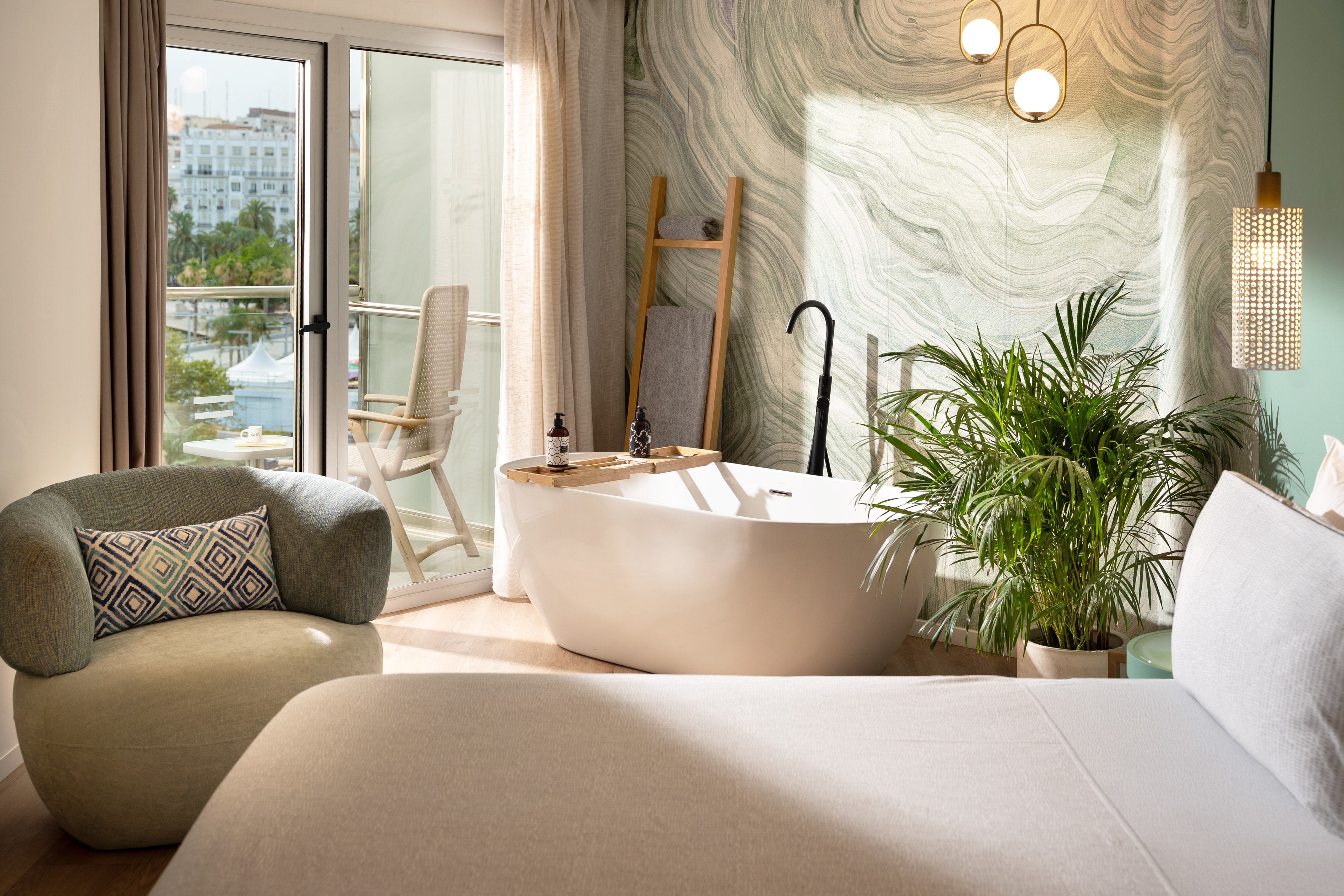 Luxury hotel suite with freestanding bathtub, balcony, and modern design.
