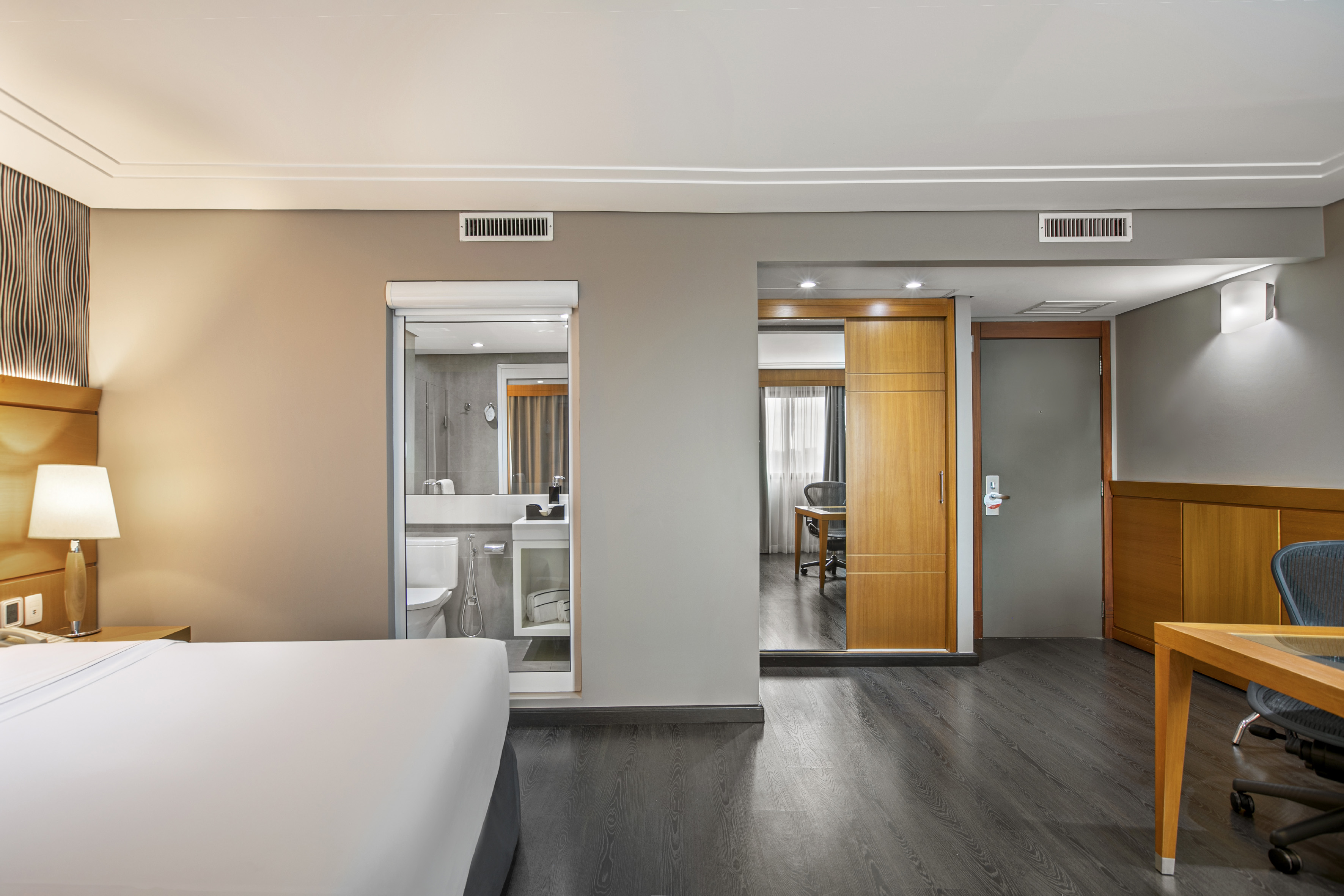Hotel suite with comfortable bed, modern bathroom, and dedicated workspace.
