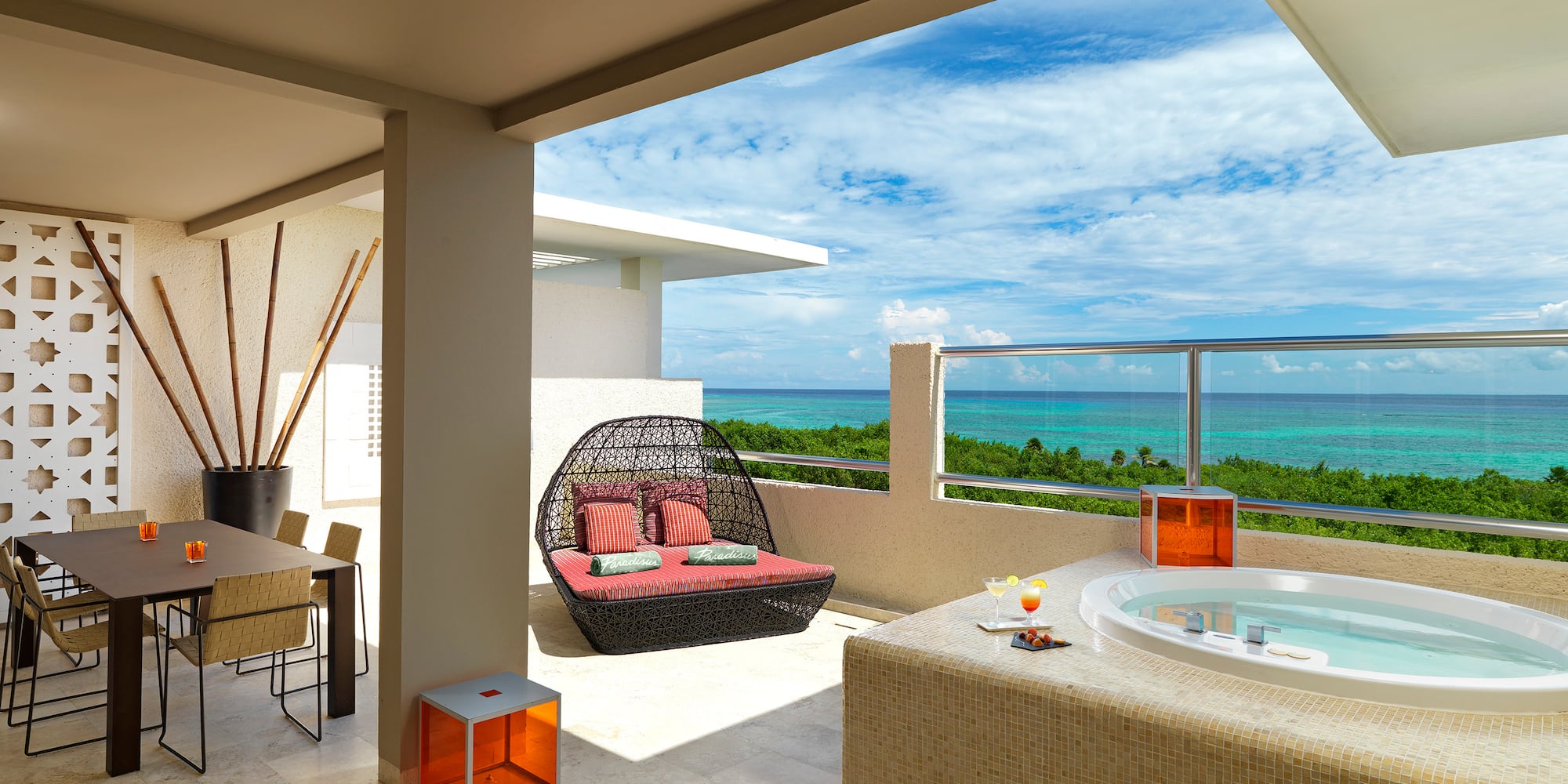 Luxury ocean view balcony with hot tub, daybed, and dining area.