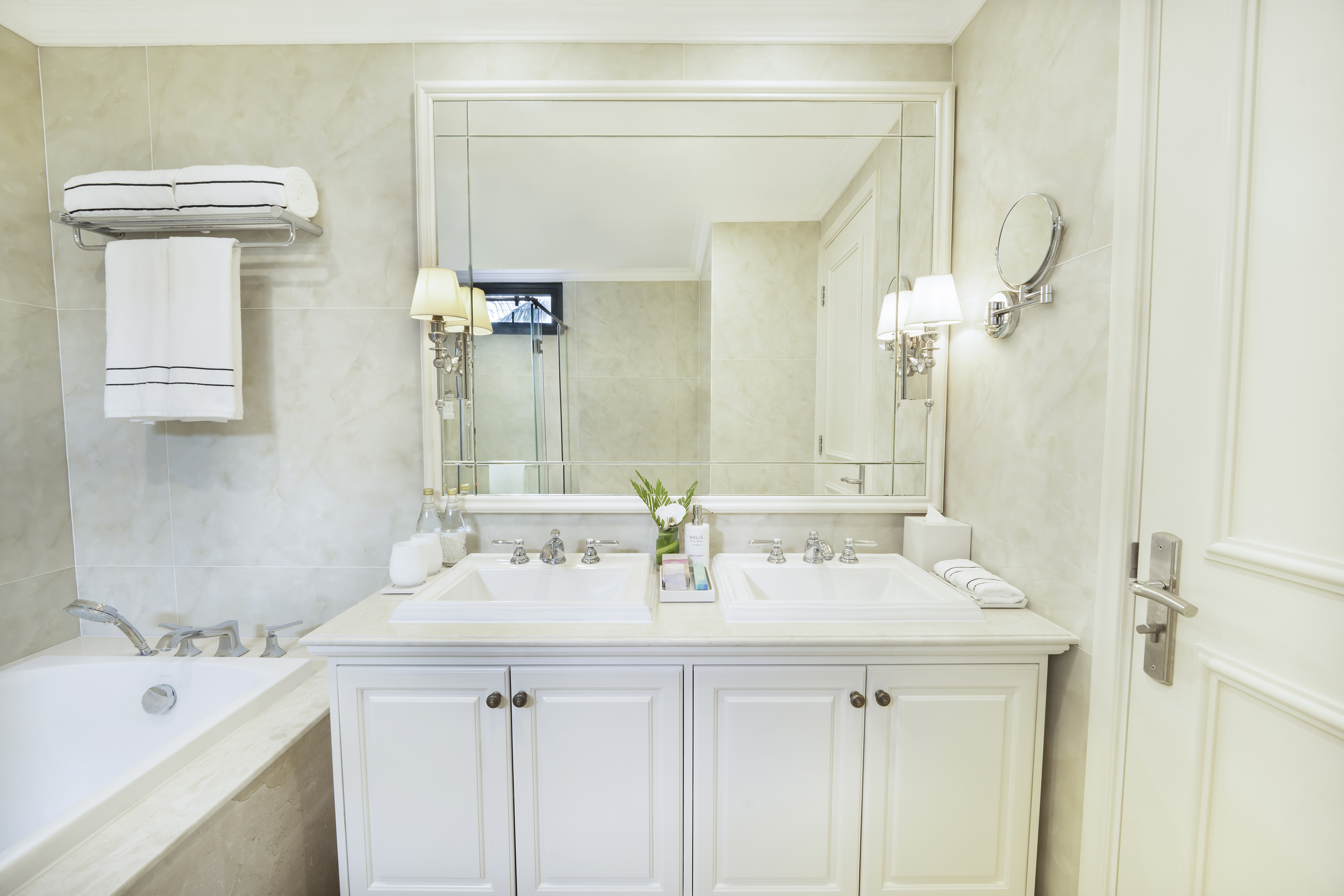 Luxury hotel bathroom with double vanity, large mirror, and bathtub.
