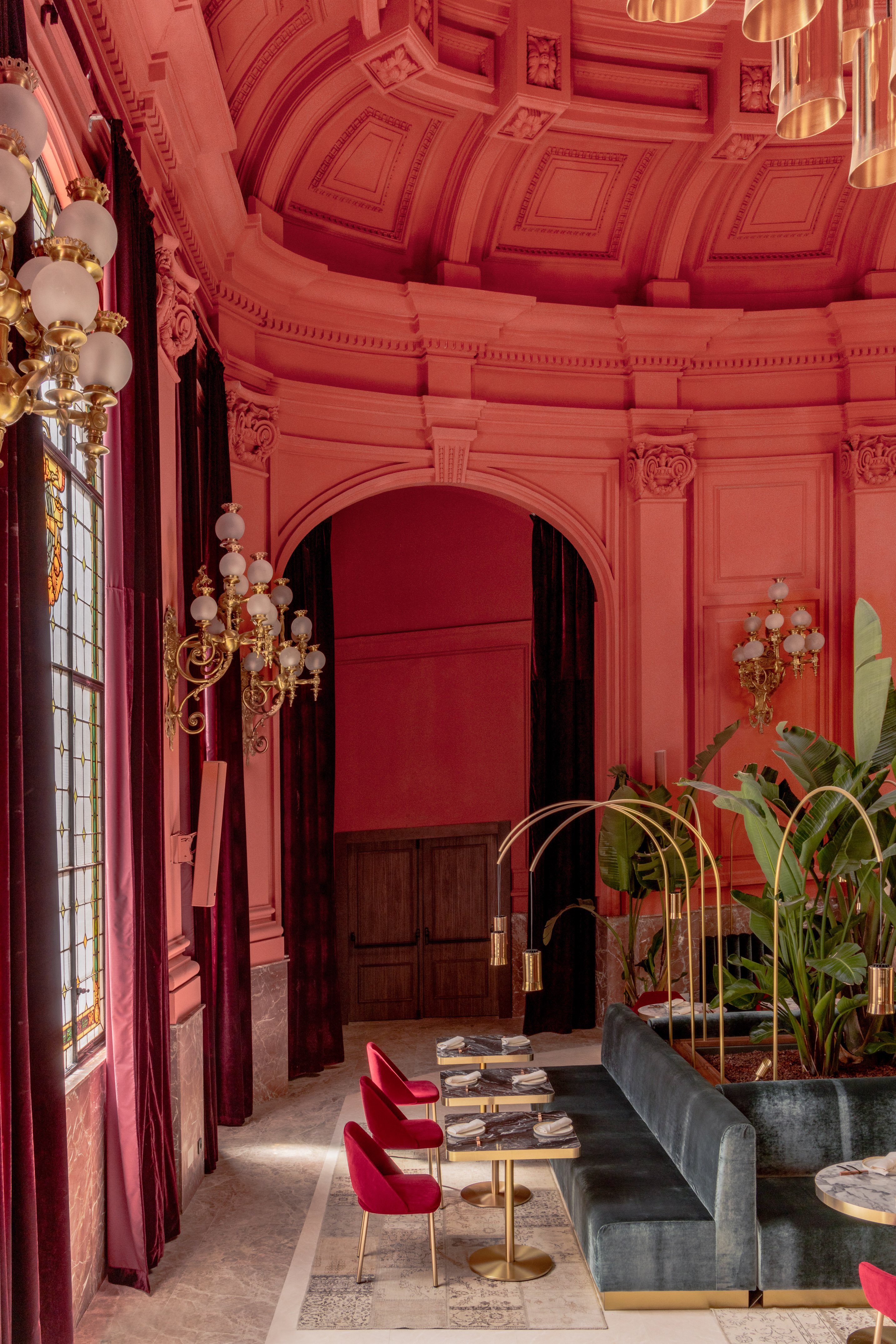 Coral restaurant interior with velvet seating, ornate ceiling, and chandeliers.