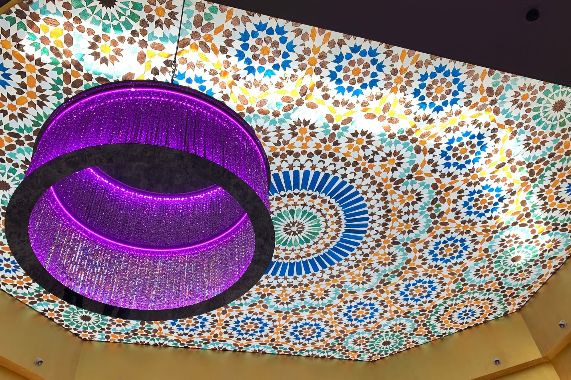 Purple crystal chandelier, colorful Moroccan geometric ceiling.