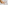 Woman petting a happy golden retriever dog on a white bed.
