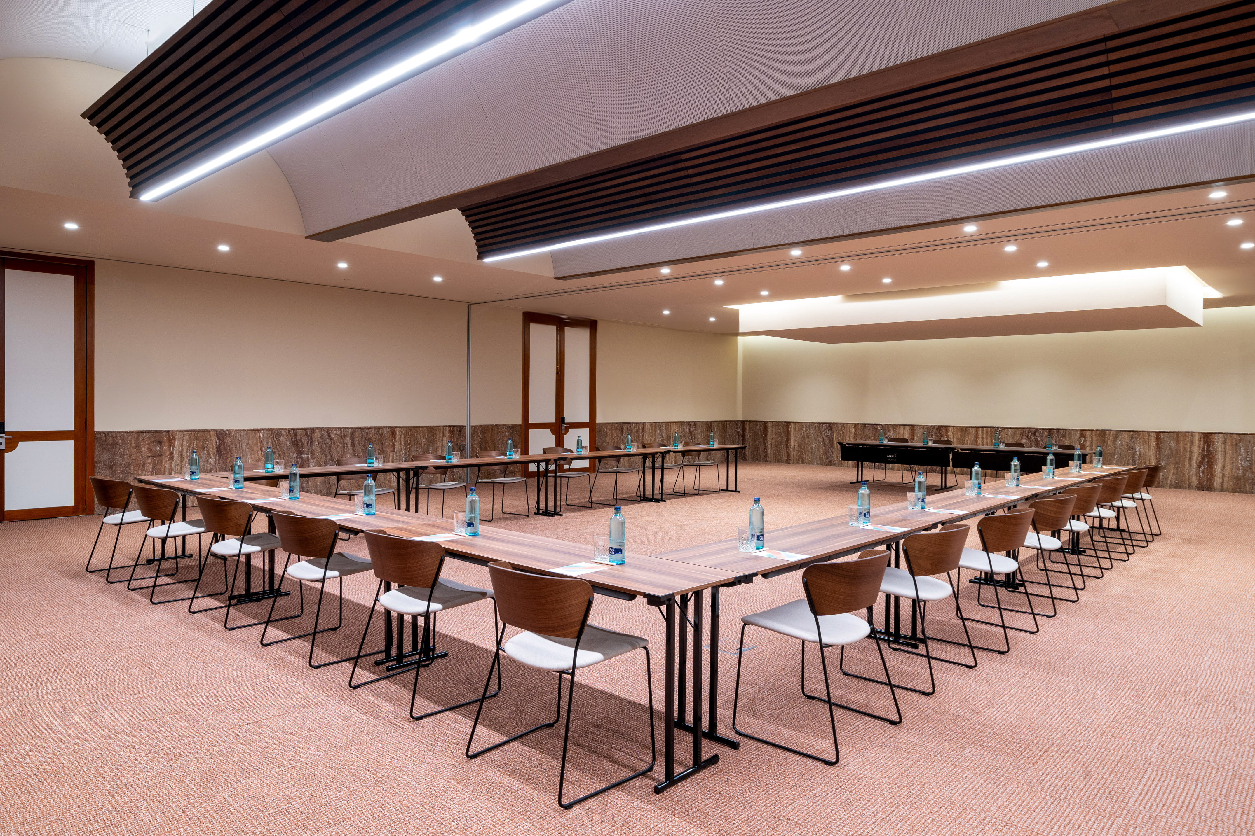 Modern U-shape conference room setup with chairs, tables, and water bottles.