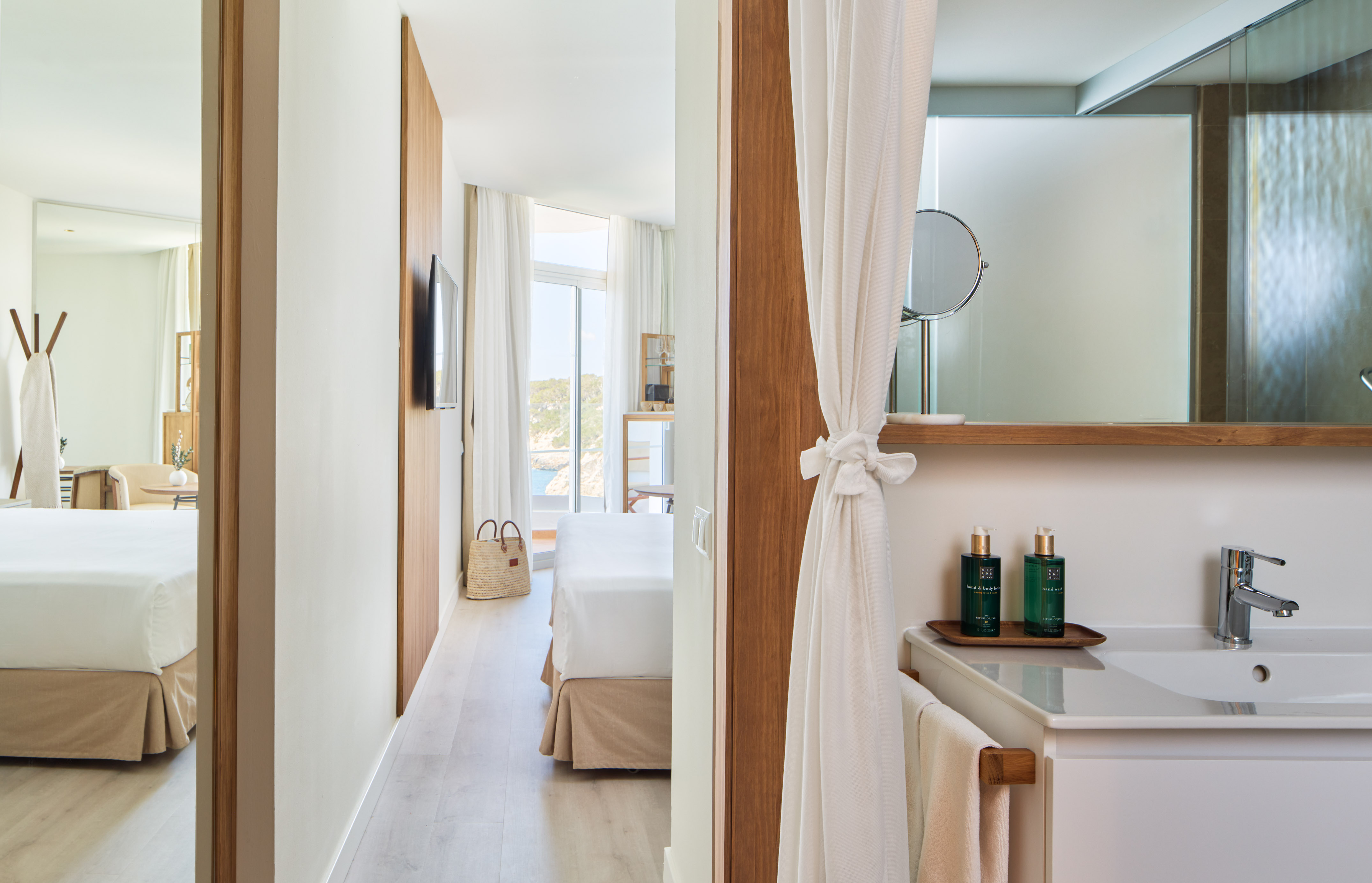 Modern hotel suite with integrated bathroom, bed, and sea view.
