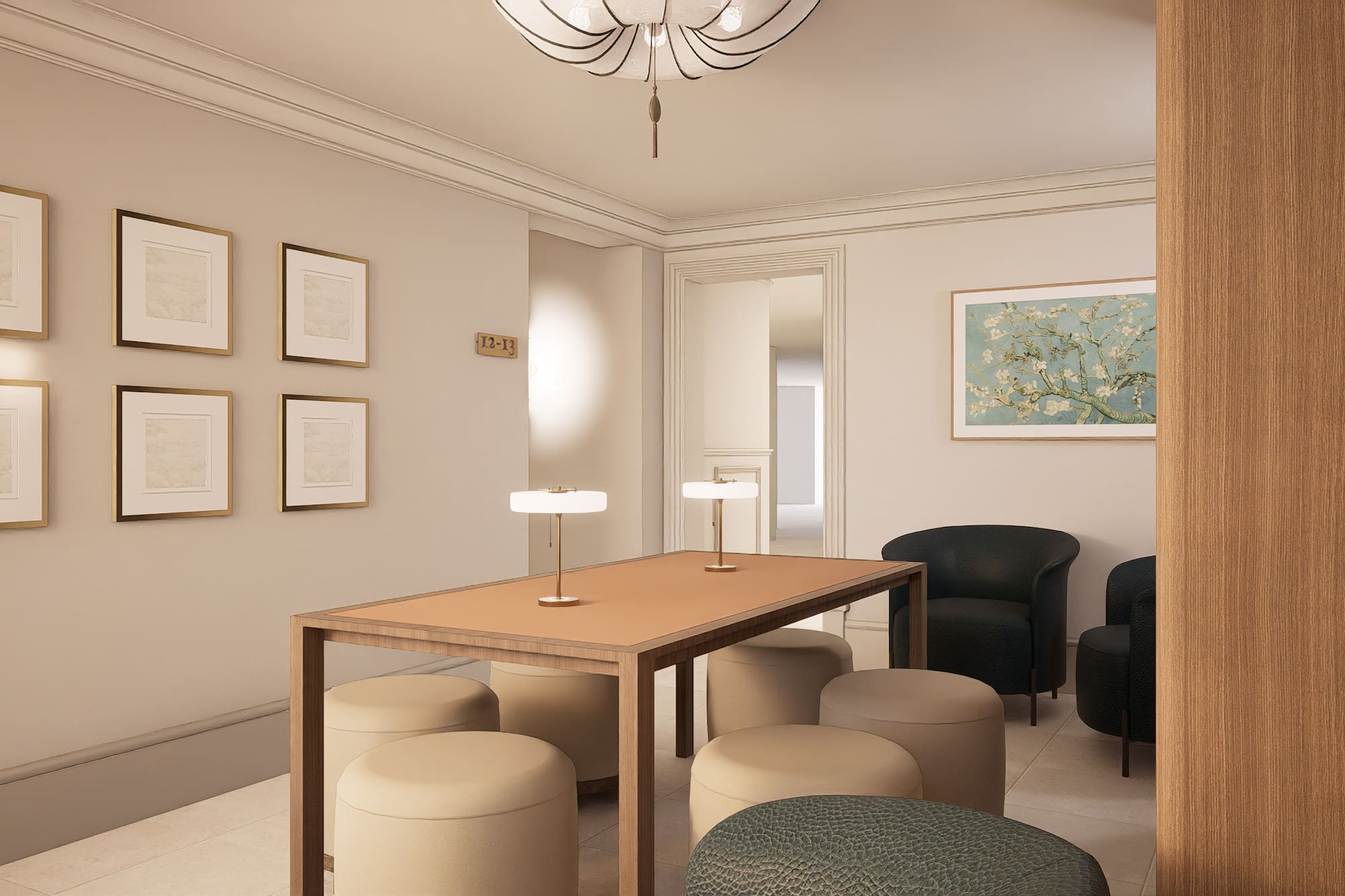 Elegant hotel lobby with meeting table, upholstered ottomans, black armchairs, and art.