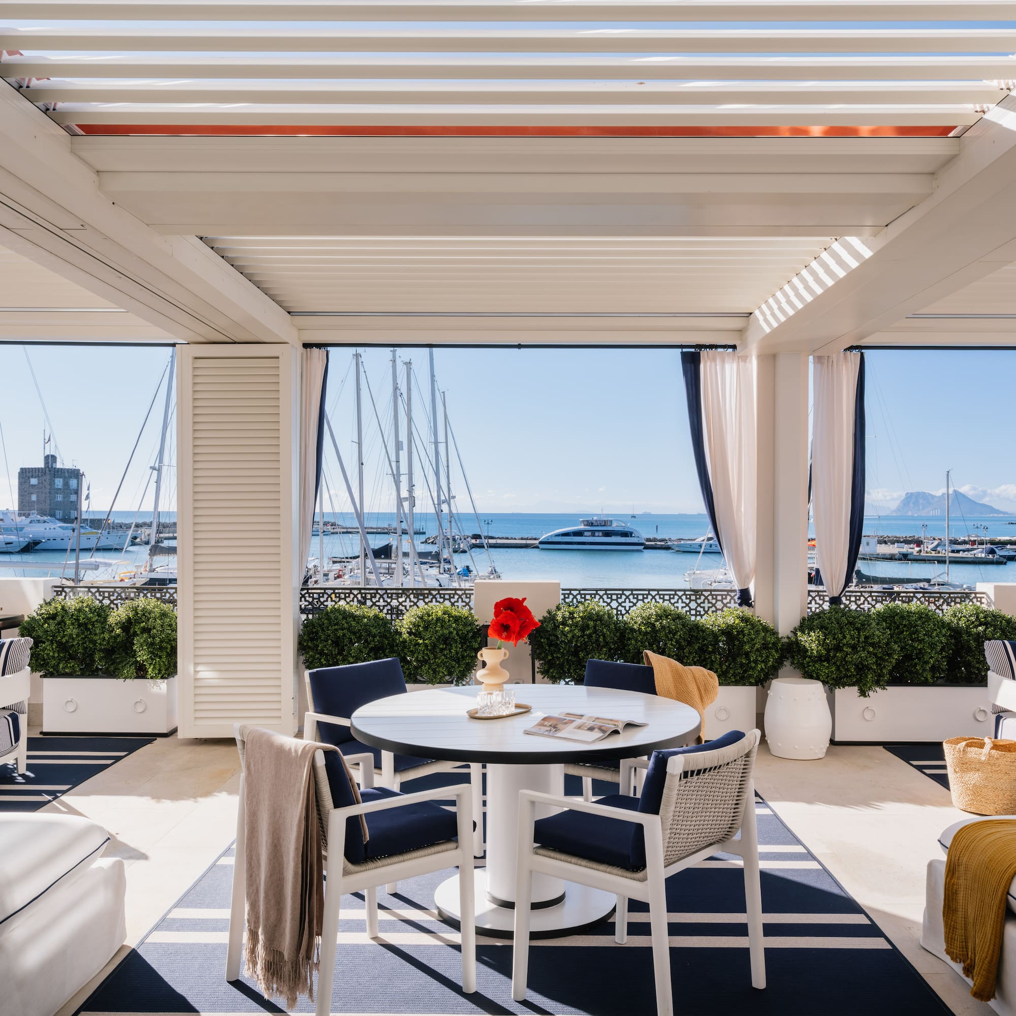 a patio with a table and chairs and a view of the water