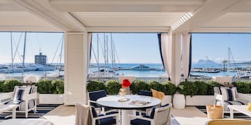 a patio with a table and chairs and a view of the water