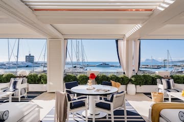 a patio with a table and chairs and a view of the water