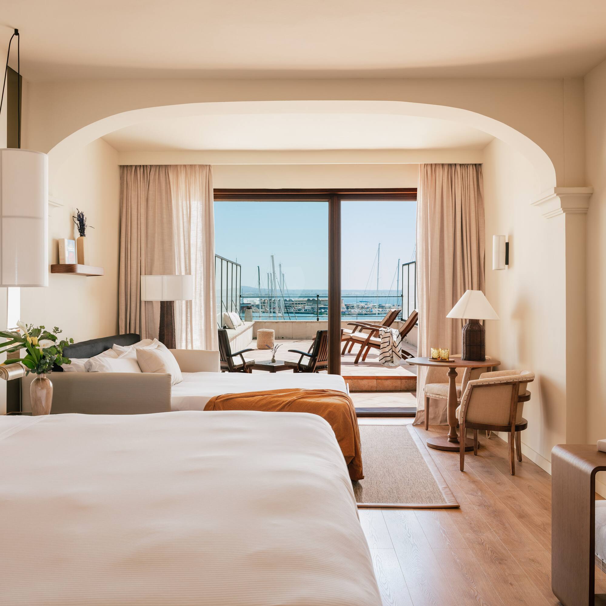 a room with two beds and a balcony with a view of the ocean