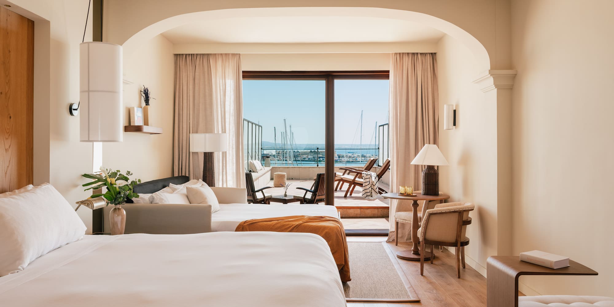 a room with two beds and a balcony with a view of the ocean