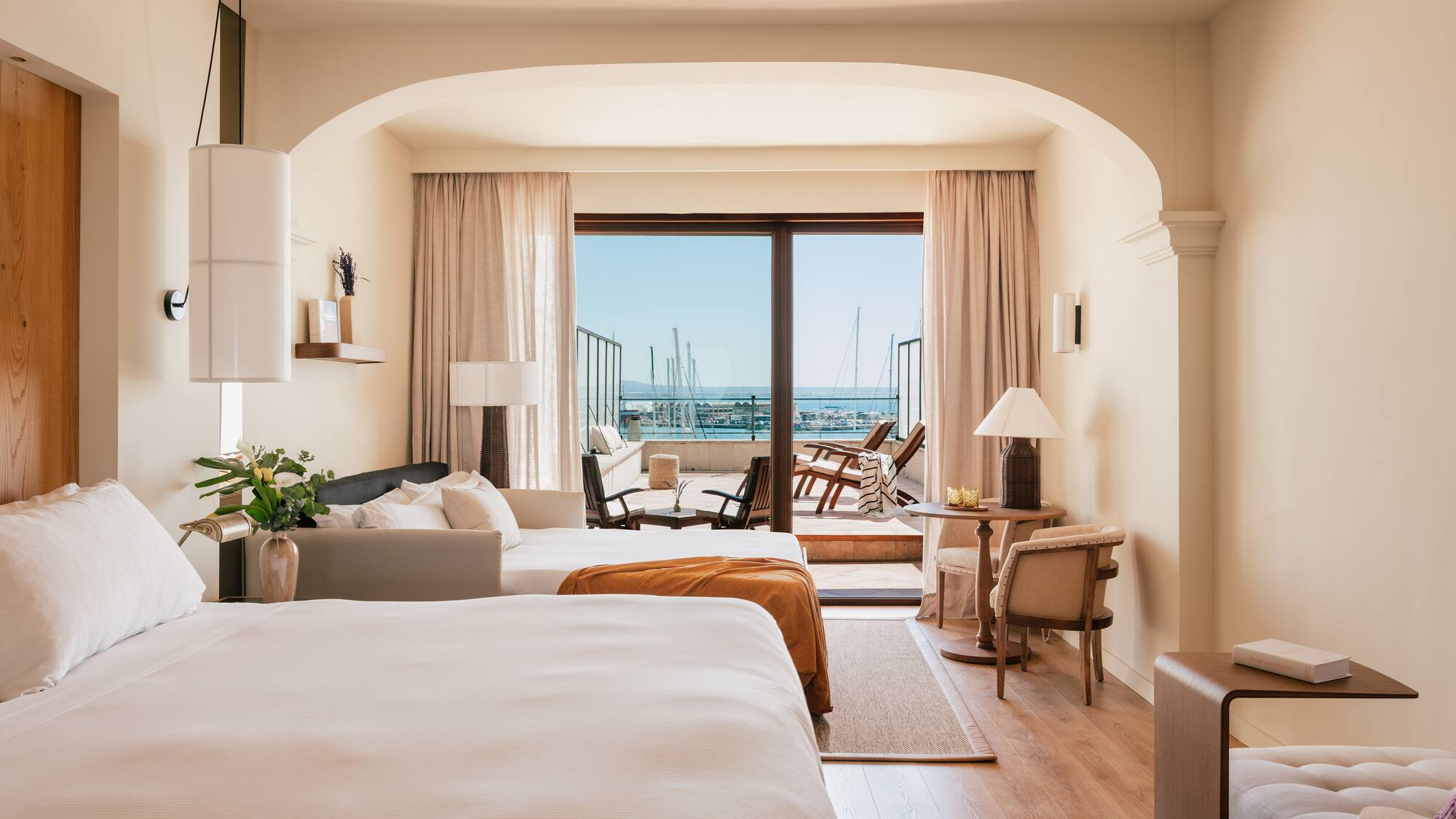 a room with two beds and a balcony with a view of the ocean