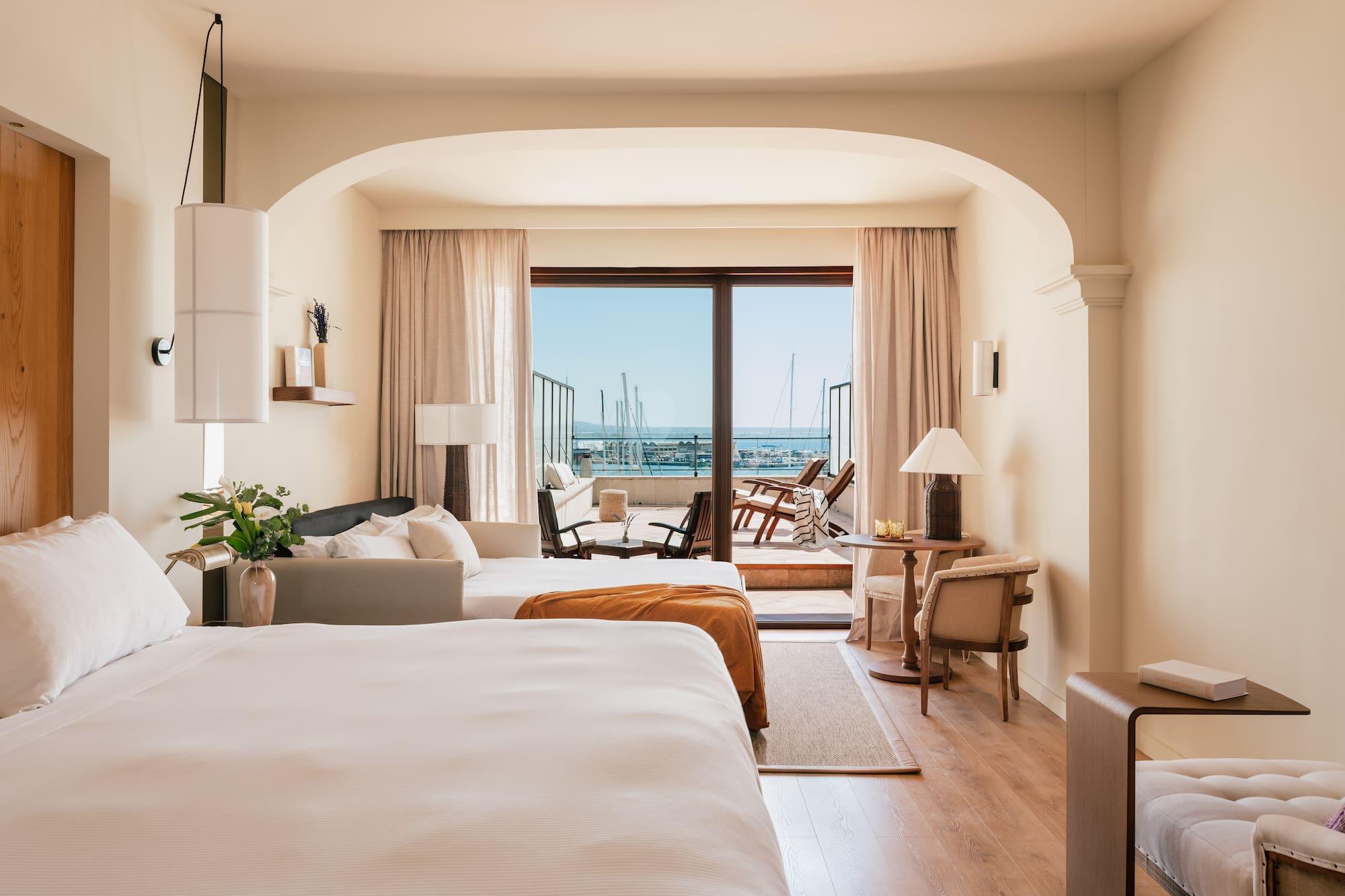 a room with two beds and a balcony with a view of the ocean