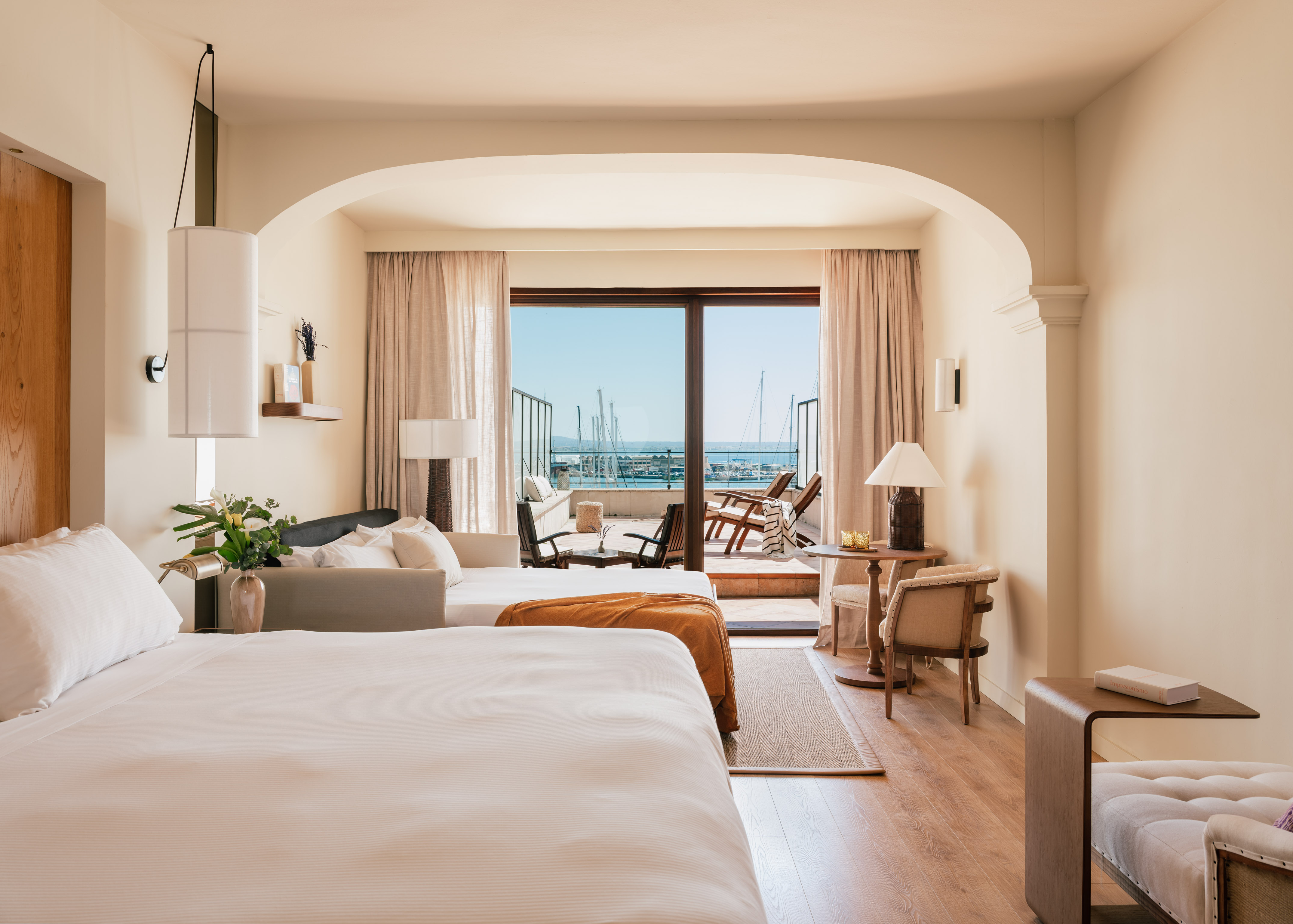 Hotel room with beds, private balcony, and panoramic marina sea view.