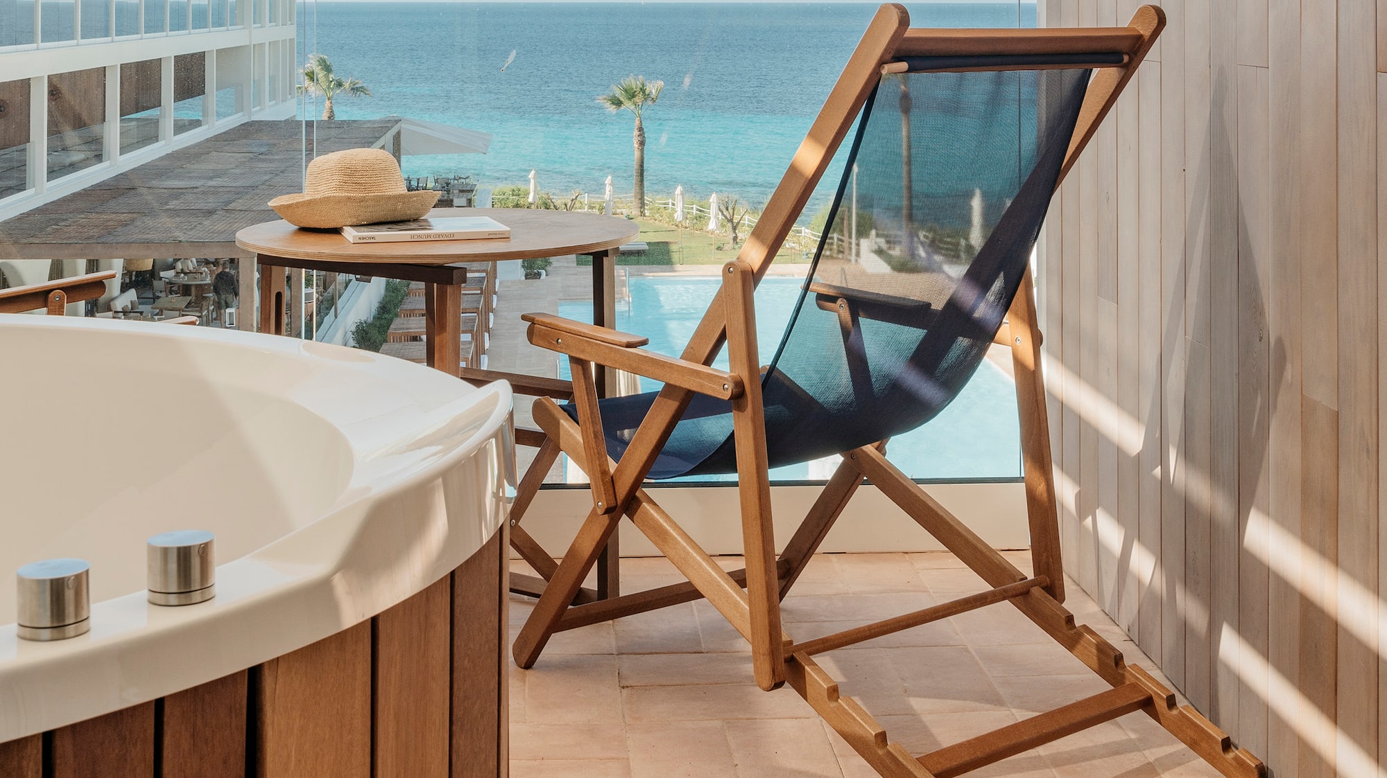 a chair and a bathtub on a balcony overlooking the ocean