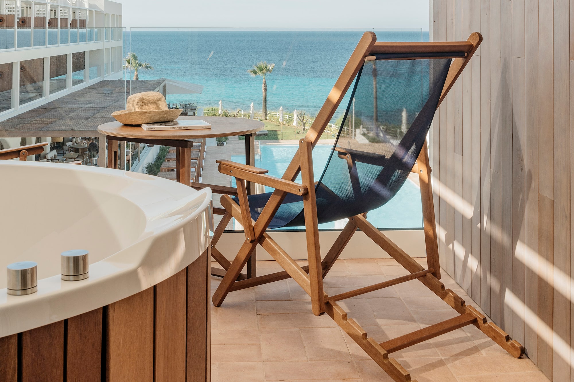 a chair and a bathtub on a balcony overlooking the ocean