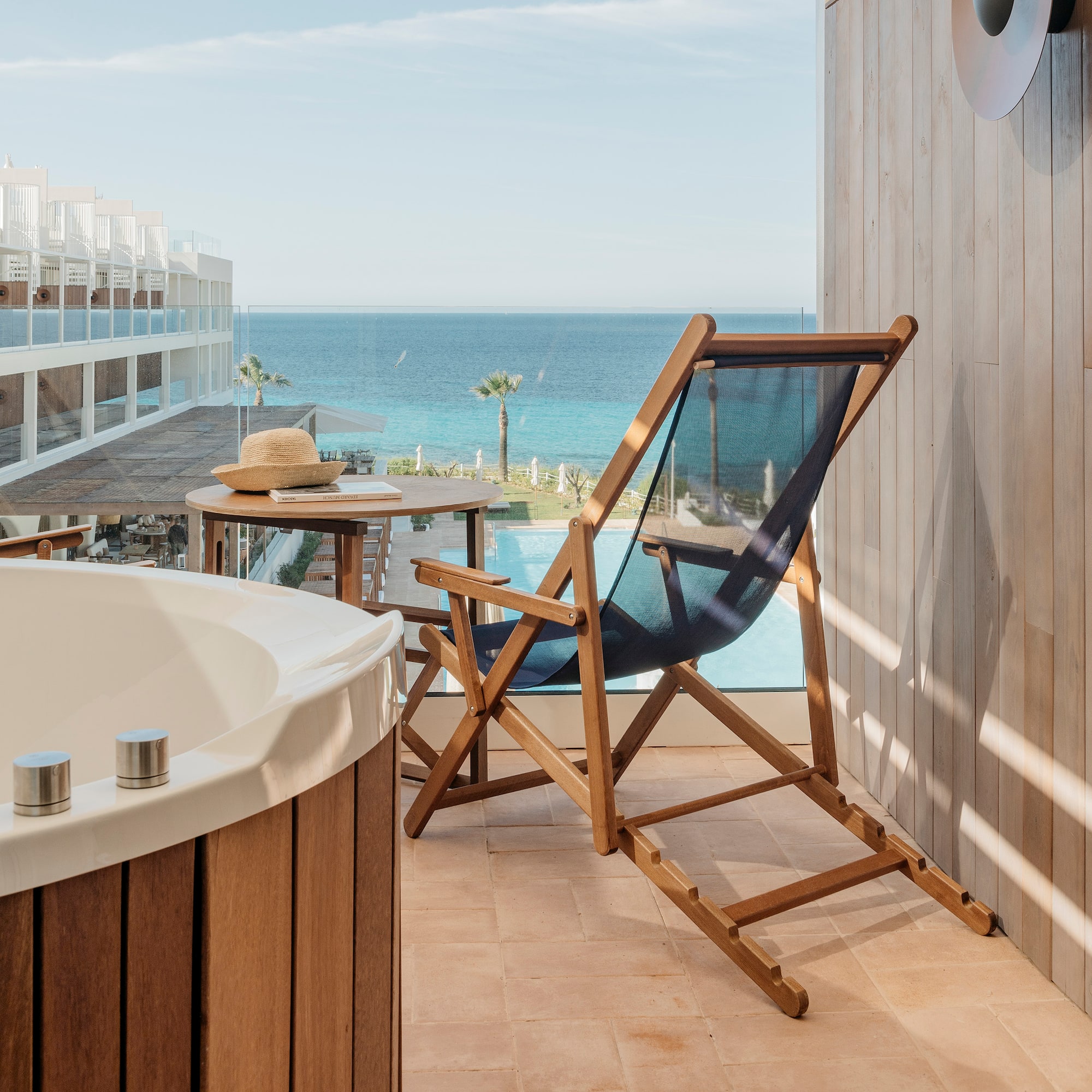 a chair and a bathtub on a balcony overlooking the ocean