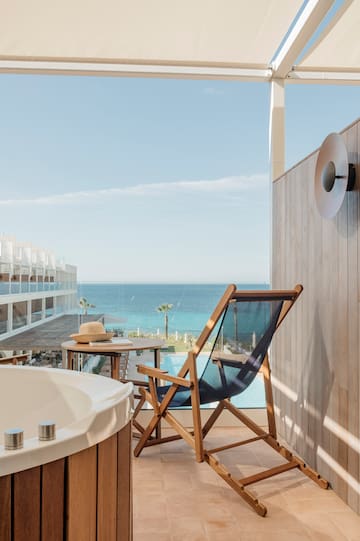 a chair and a bathtub on a balcony overlooking the ocean